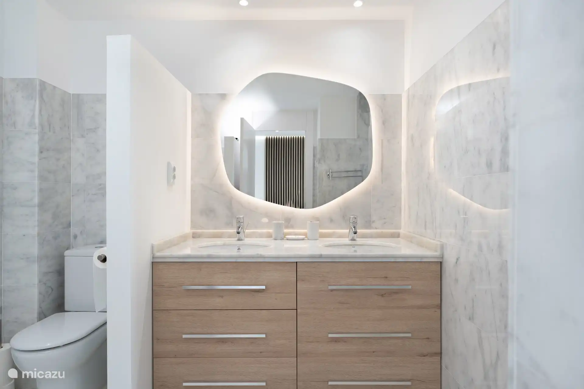 Double vasque avec finitions en marbre, miroir rétroéclairé et beaucoup de rangement.