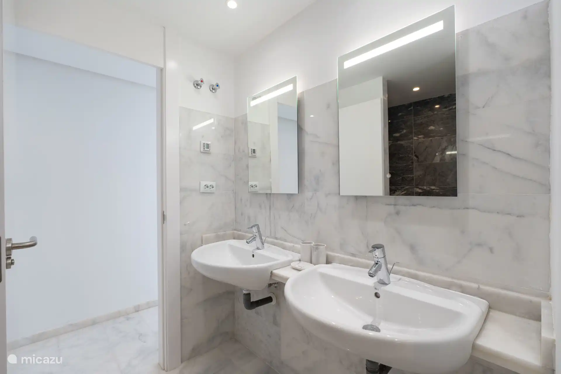 Salle de bain avec double vasque et miroirs éclairés.