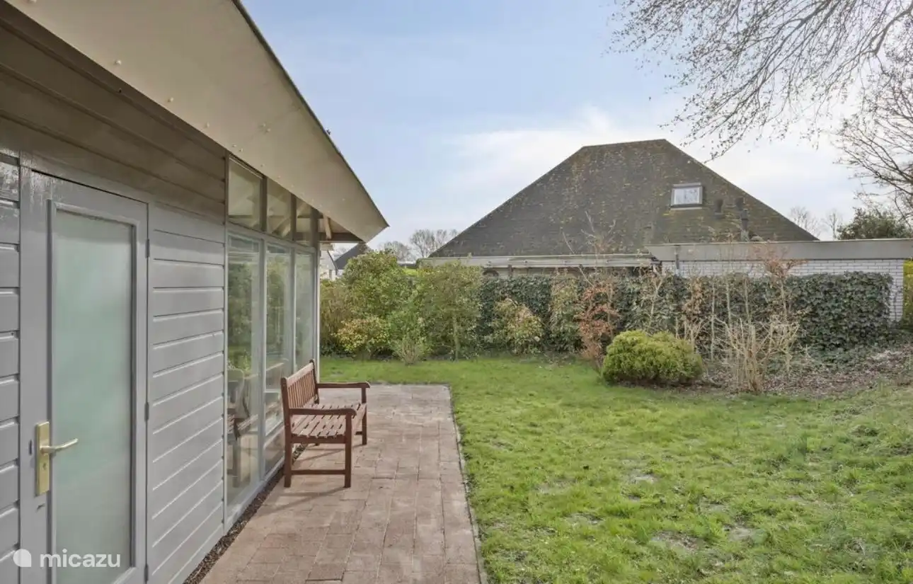 Attraktive Seitenterrasse mit Gartenbank und Blick ins Grüne – der perfekte Ort für eine Tasse Kaffee in der Sonne.