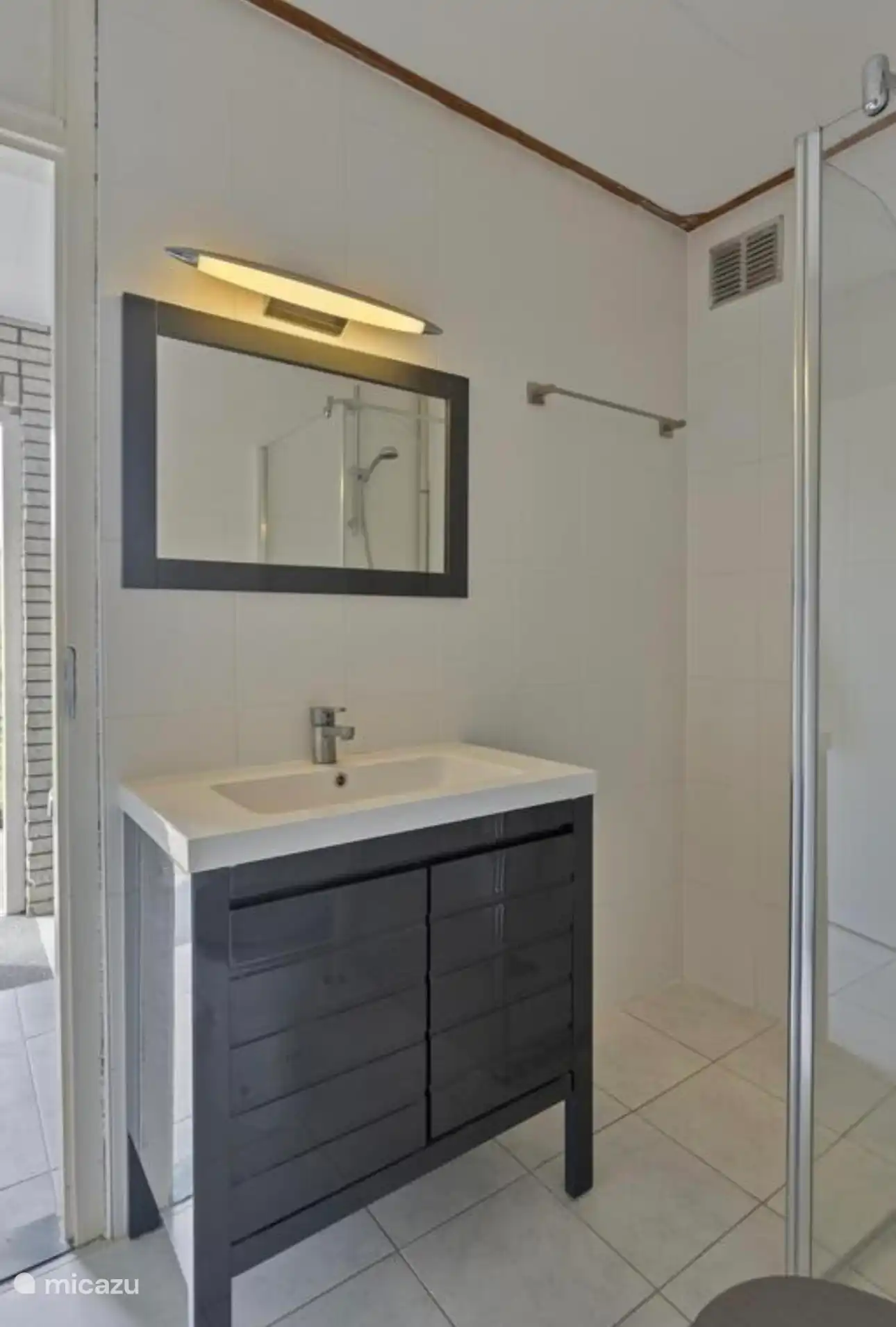 Frisches und gepflegtes Badezimmer mit modernem Waschbecken und begehbarer Dusche, direkt vom Haus aus zugänglich.