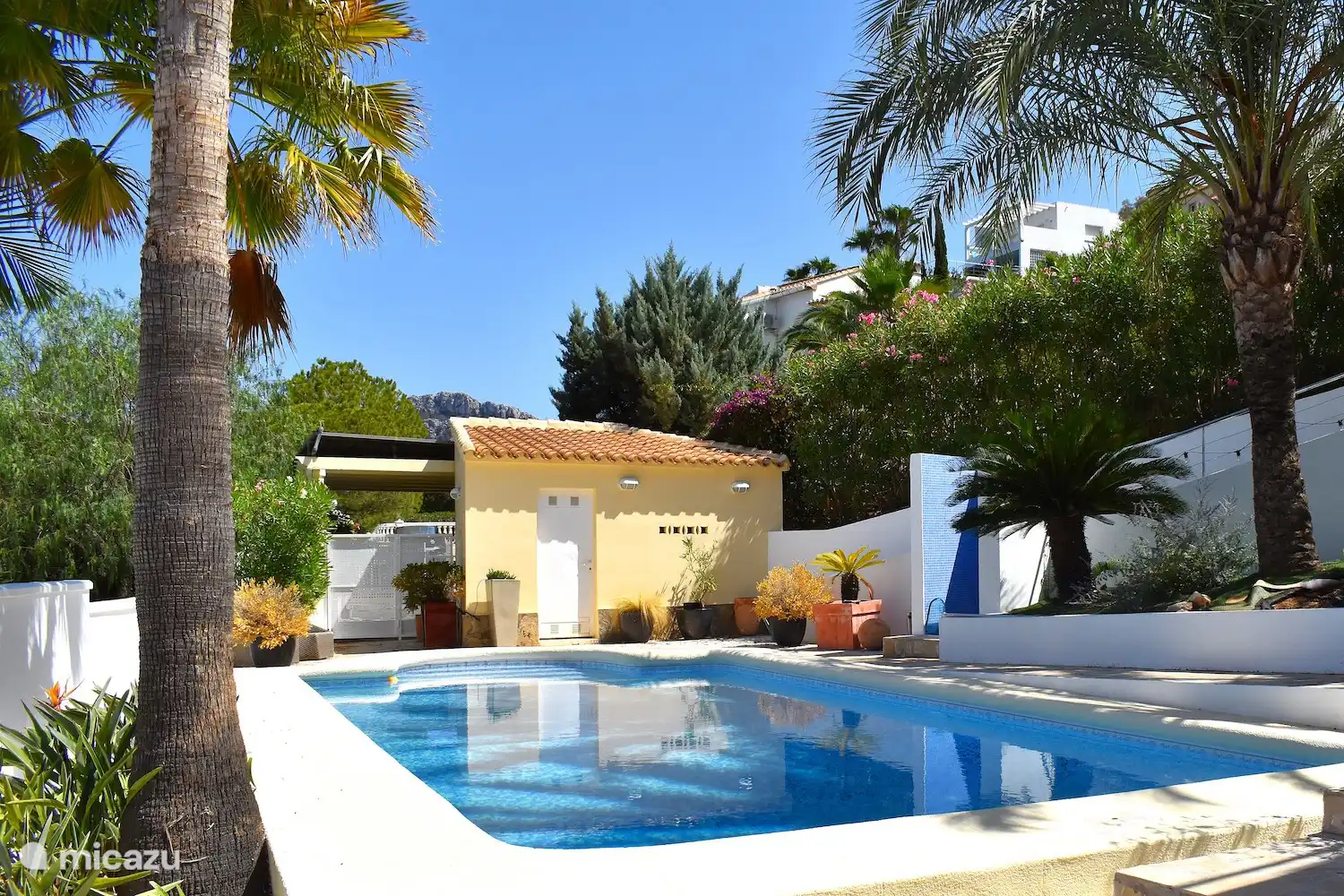 Vue sur la piscine et le pool house.
À l’arrière gauche, vous voyez l’abri d’auto où vous pouvez garer votre voiture à l’ombre.