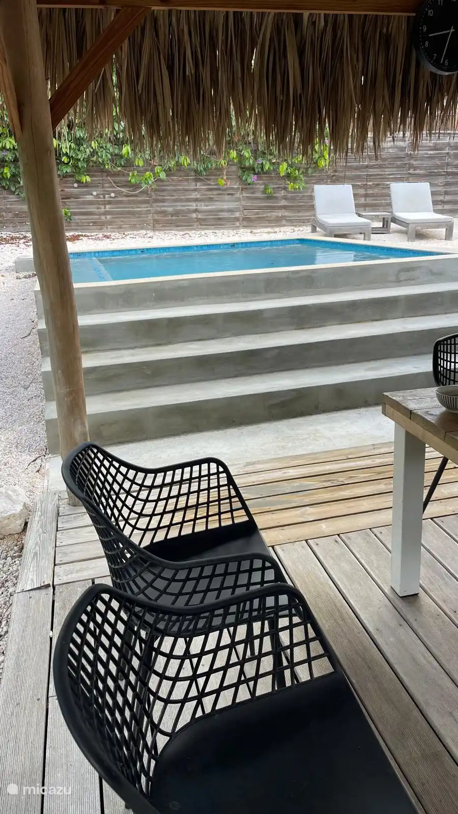 Privé zwembad in tropische tuin bij terras.