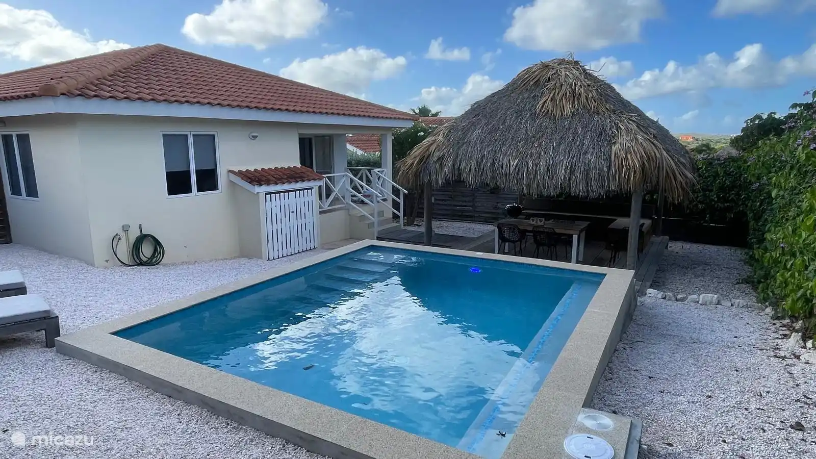 Privé zwembad, terras met Palapa, eettafel, lounge set en BBQ in tropische tuin.