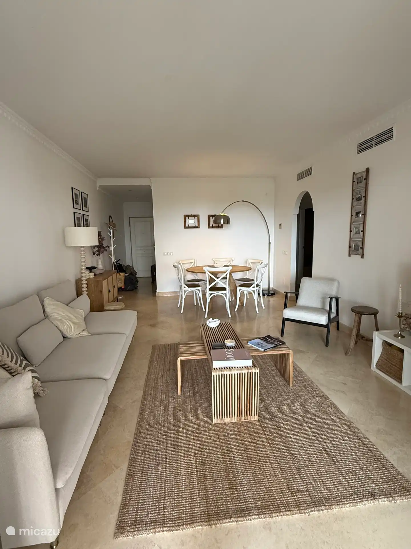 Luxuriöses Wohnzimmer im ruhigen Ibiza-Stil, geräumiges Sofa und gemütlicher Esstisch