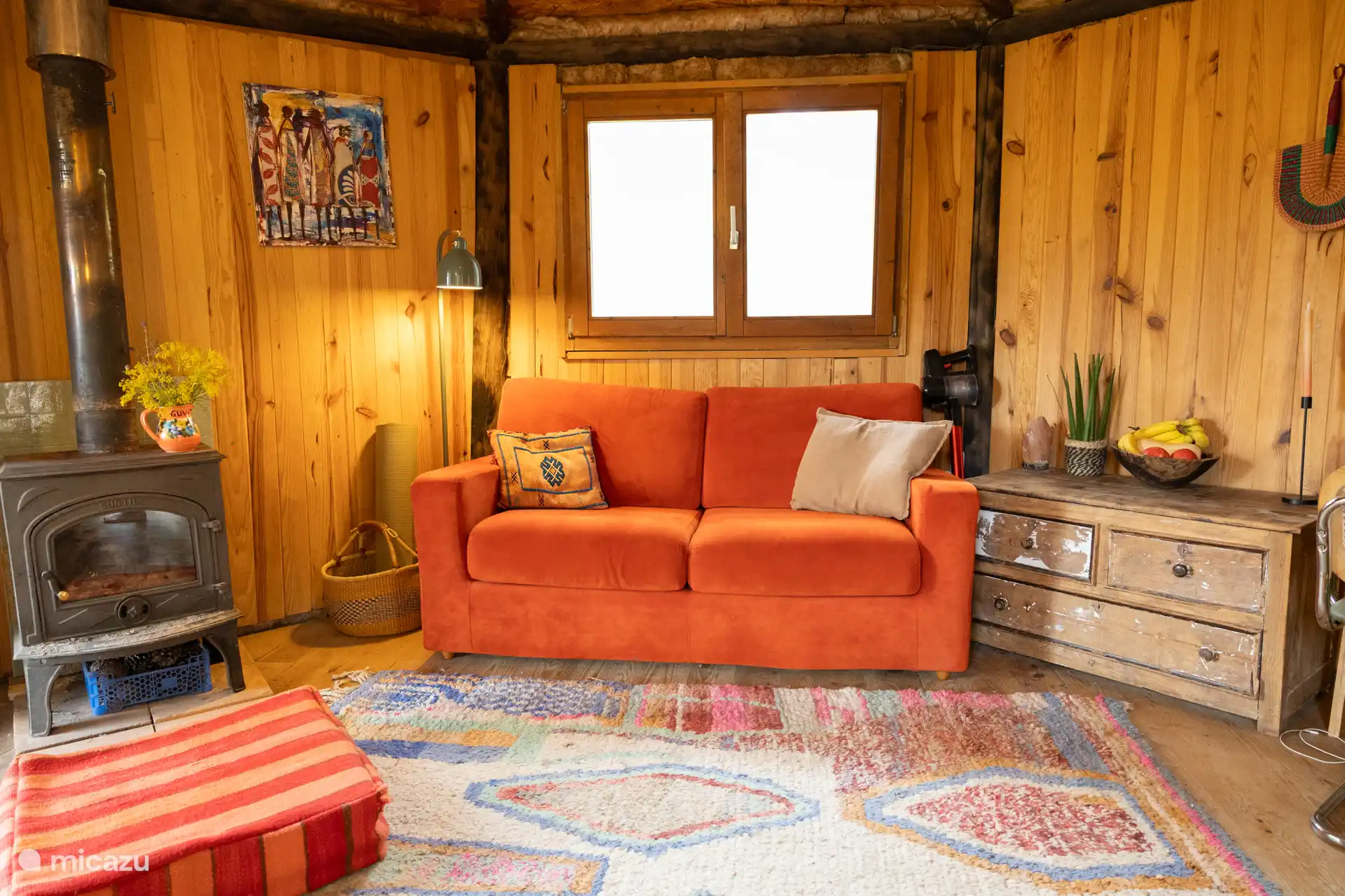 The tiny house inside with a nice two-seater sofa, ottoman and fireplace