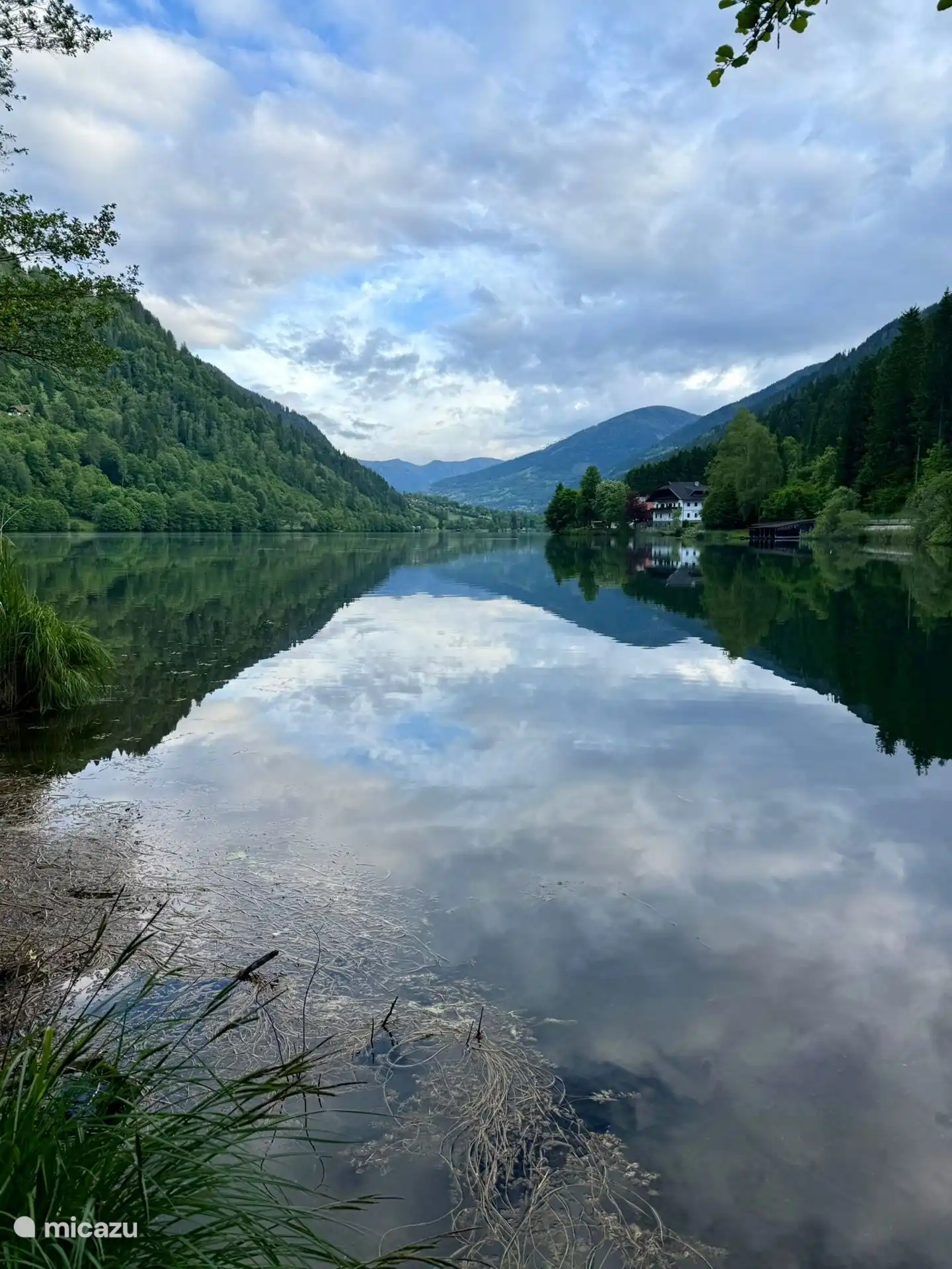 Stimmungsvolles Foto des Gebäudes, umgeben von Bergen, am See