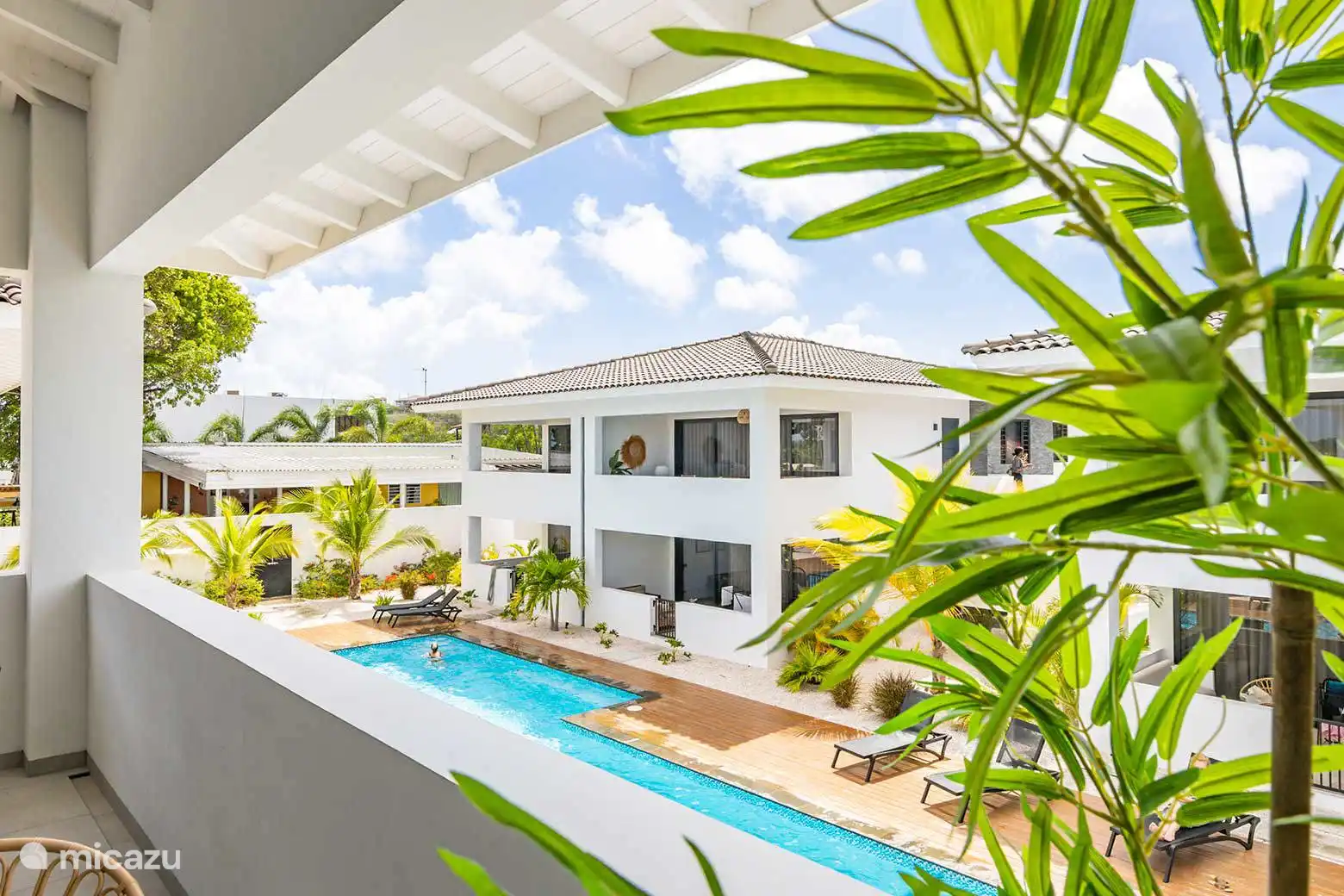 Balcón con comedor y sala de estar y vista a la piscina