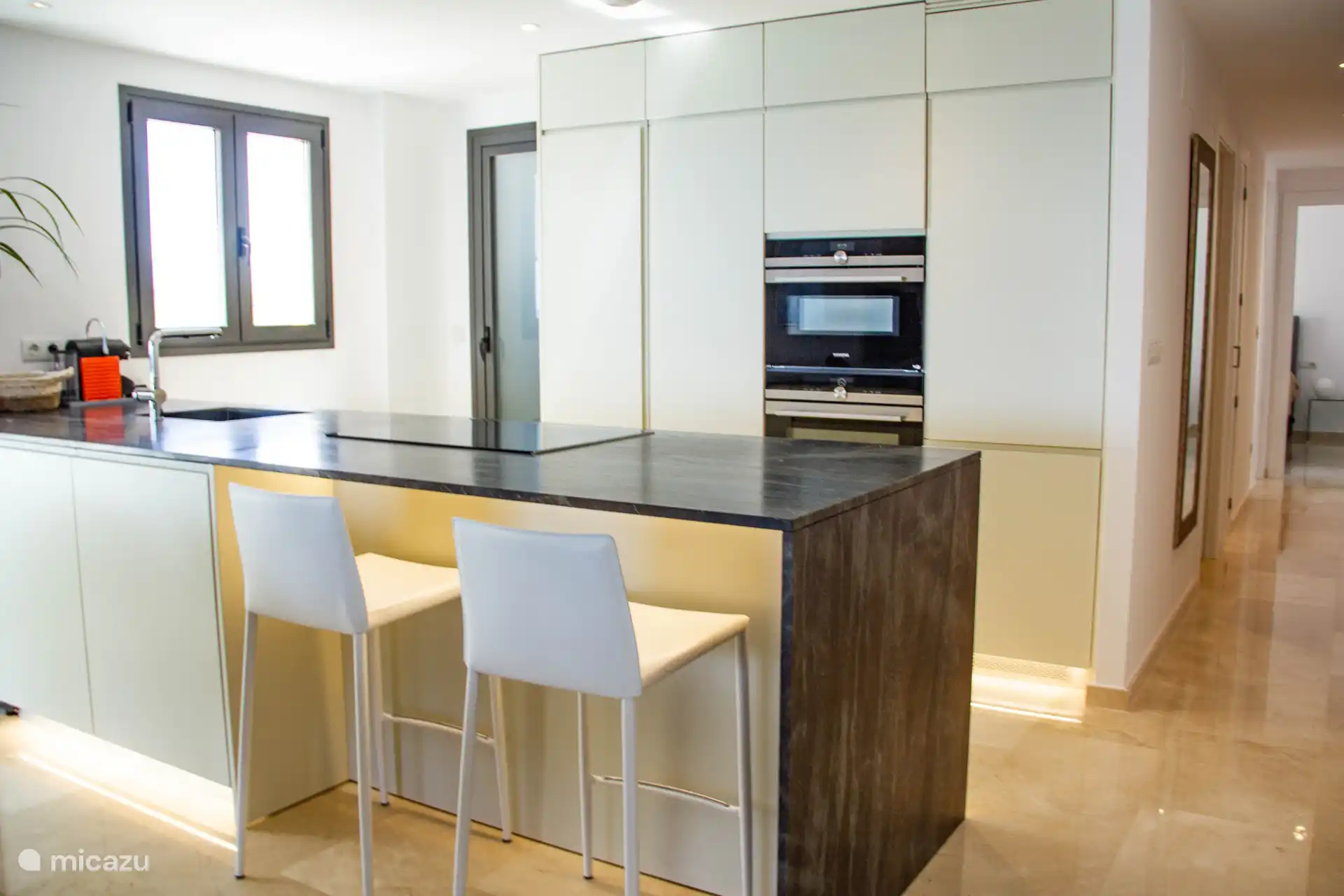 Die offene Küche verfügt über einen Gefrierschrank, einen Kühlschrank, einen Geschirrspüler, einen Backofen, ein Induktionskochfeld, einen Toaster, eine Nespresso-Kaffeemaschine, eine Kombimikrowelle, einen Weinklimaschrank und einen Wasserkocher.