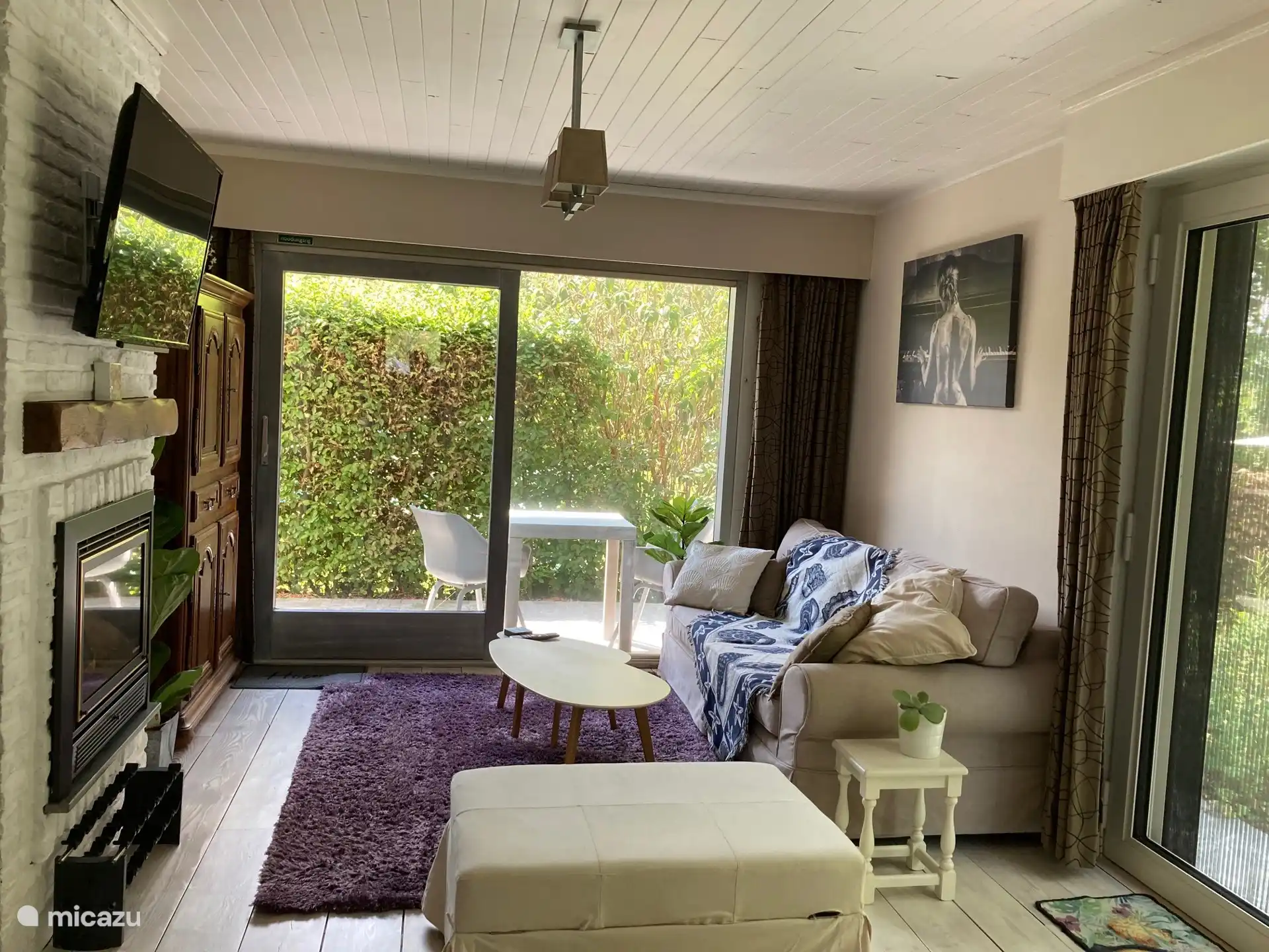 salon met 3-zits sofabed met lattenbodem, barkast, gashaard, TV op internet, poef met binnenin bedlinnen voor sofabed, toegang tot overdekt terras aan keuken en rechts toegangsdeur naar groot terras.