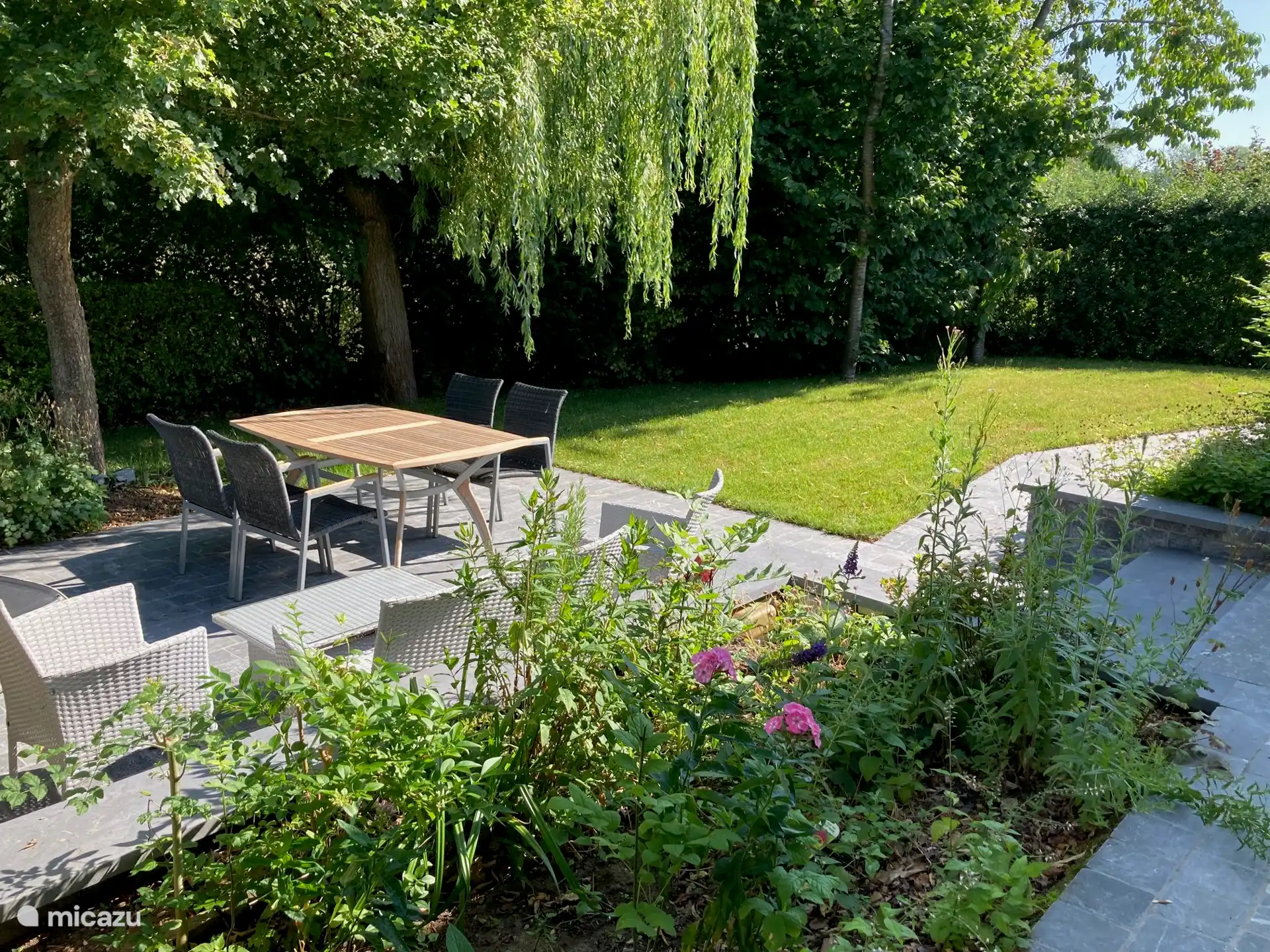 Tuin met privaat terras met trap naar de woning (met ledverlichting voor 's avond) en ook een hellend pad voor minder mobiele mensen naar de oprit.