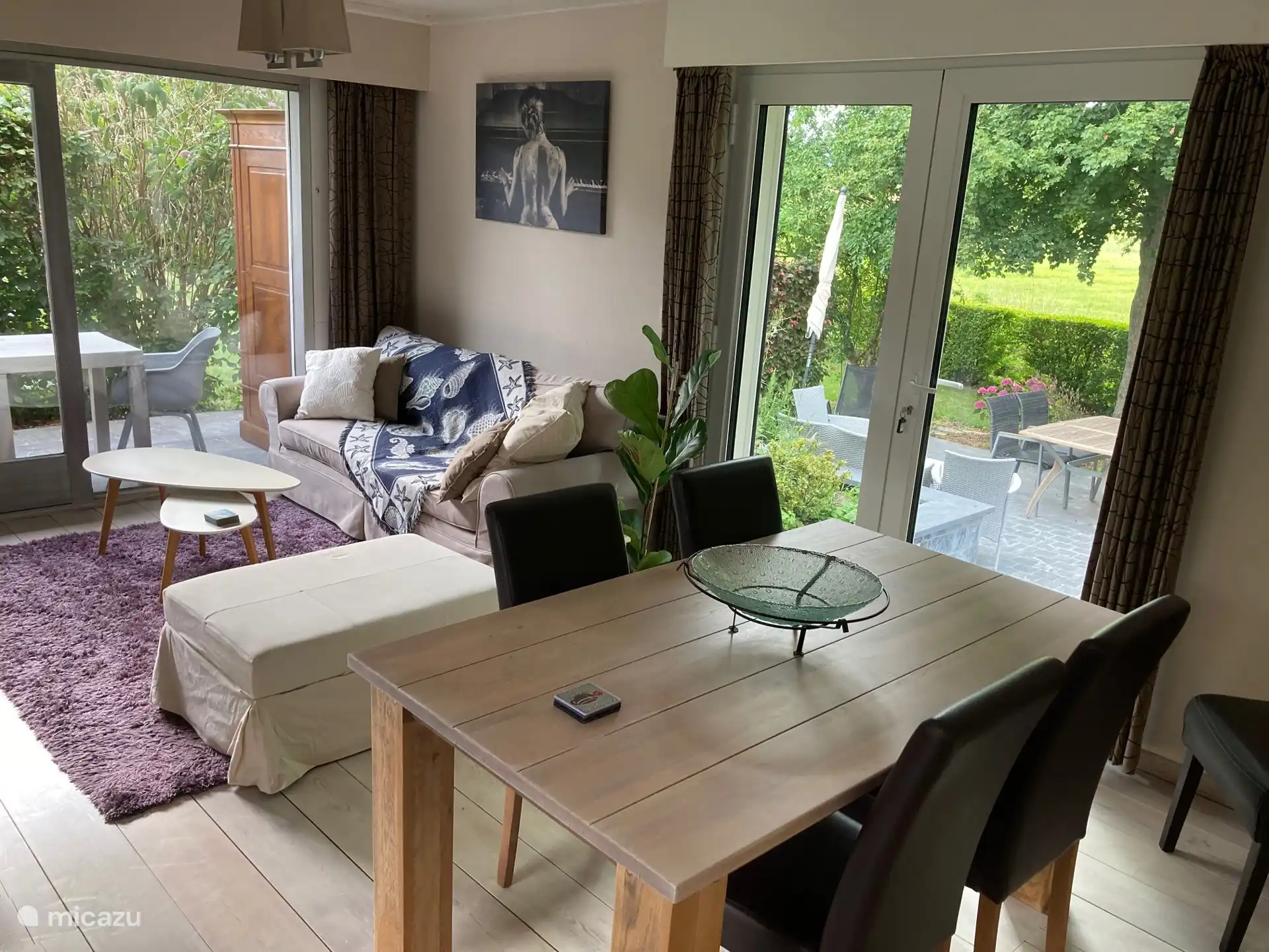 woonkamer met salon en eetplaats met zicht op tuin en overdekt terras met tuinkast voor tuinkussens, bezem, speelgoed e.a.