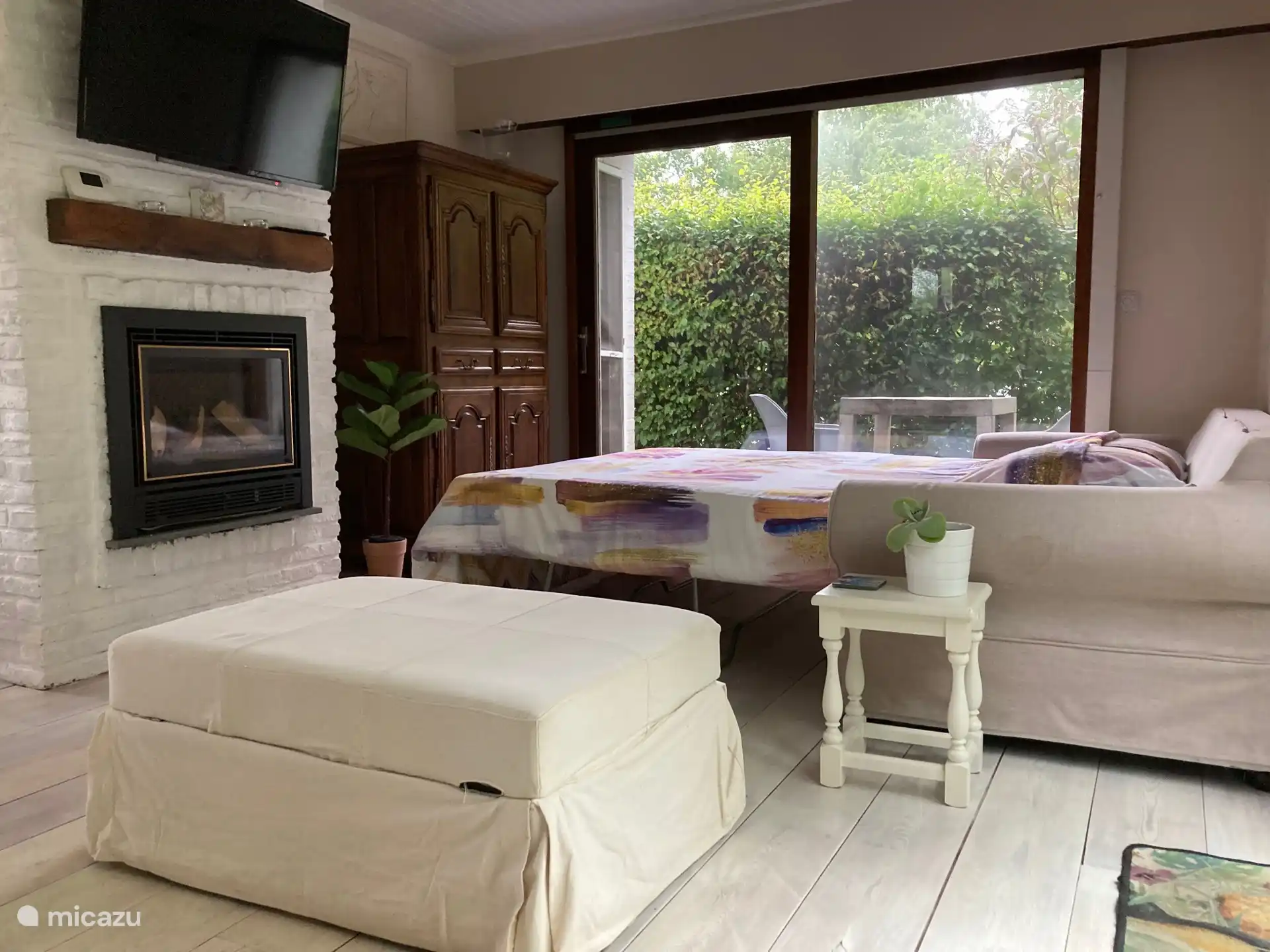 2 persoons sofabed in living met toebehoren in poef.