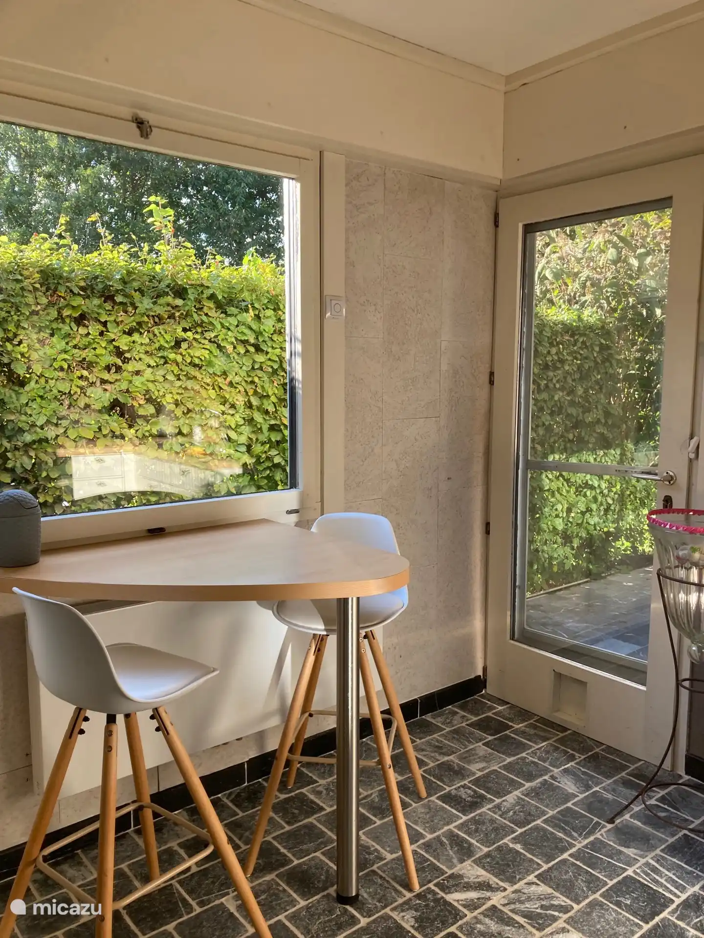 Keuken met achterdeur naar overdekt terras en eethoek met barstoelen