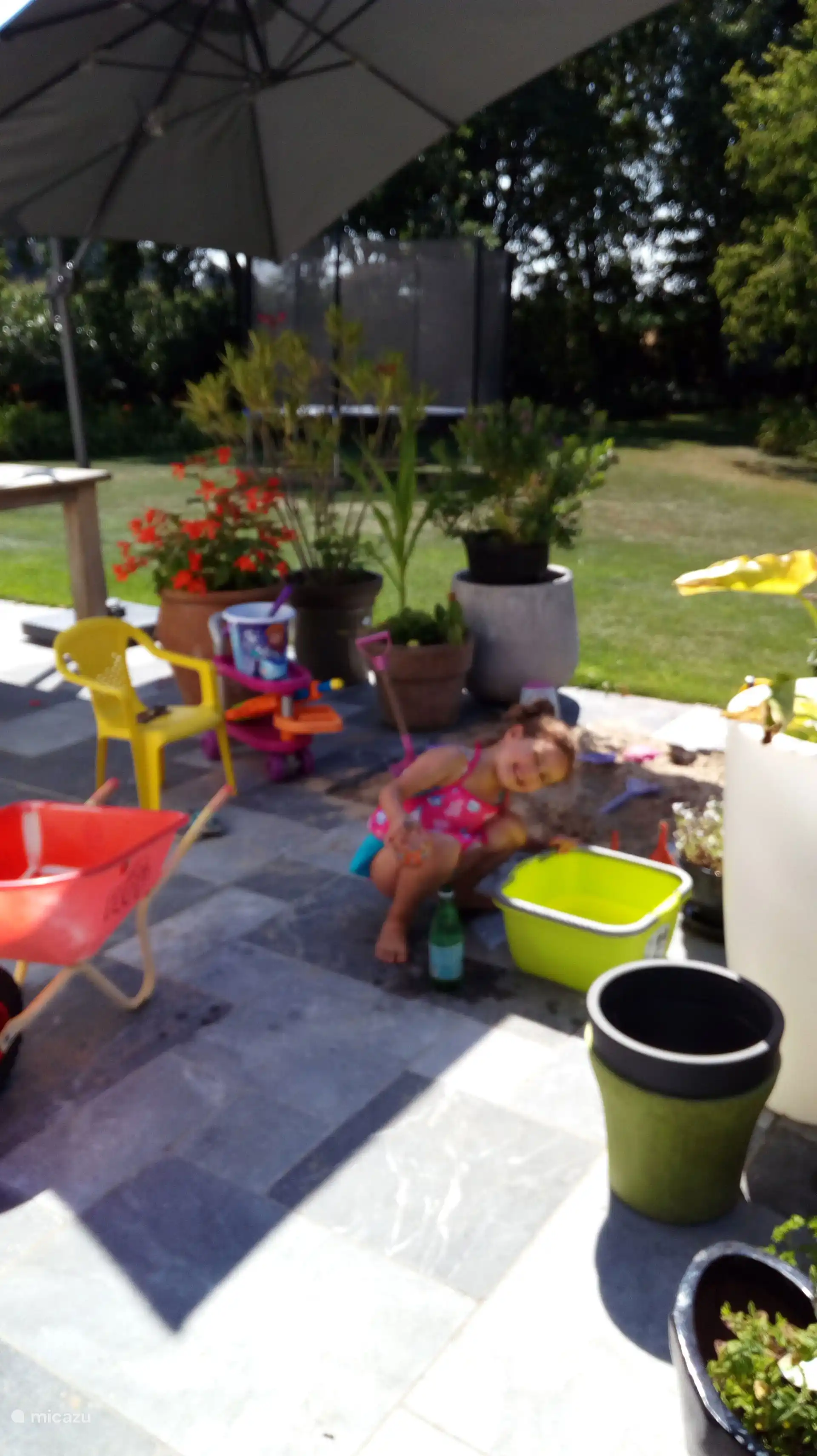 Zandbak met zandspeeltjes en kinderstoel en parasol