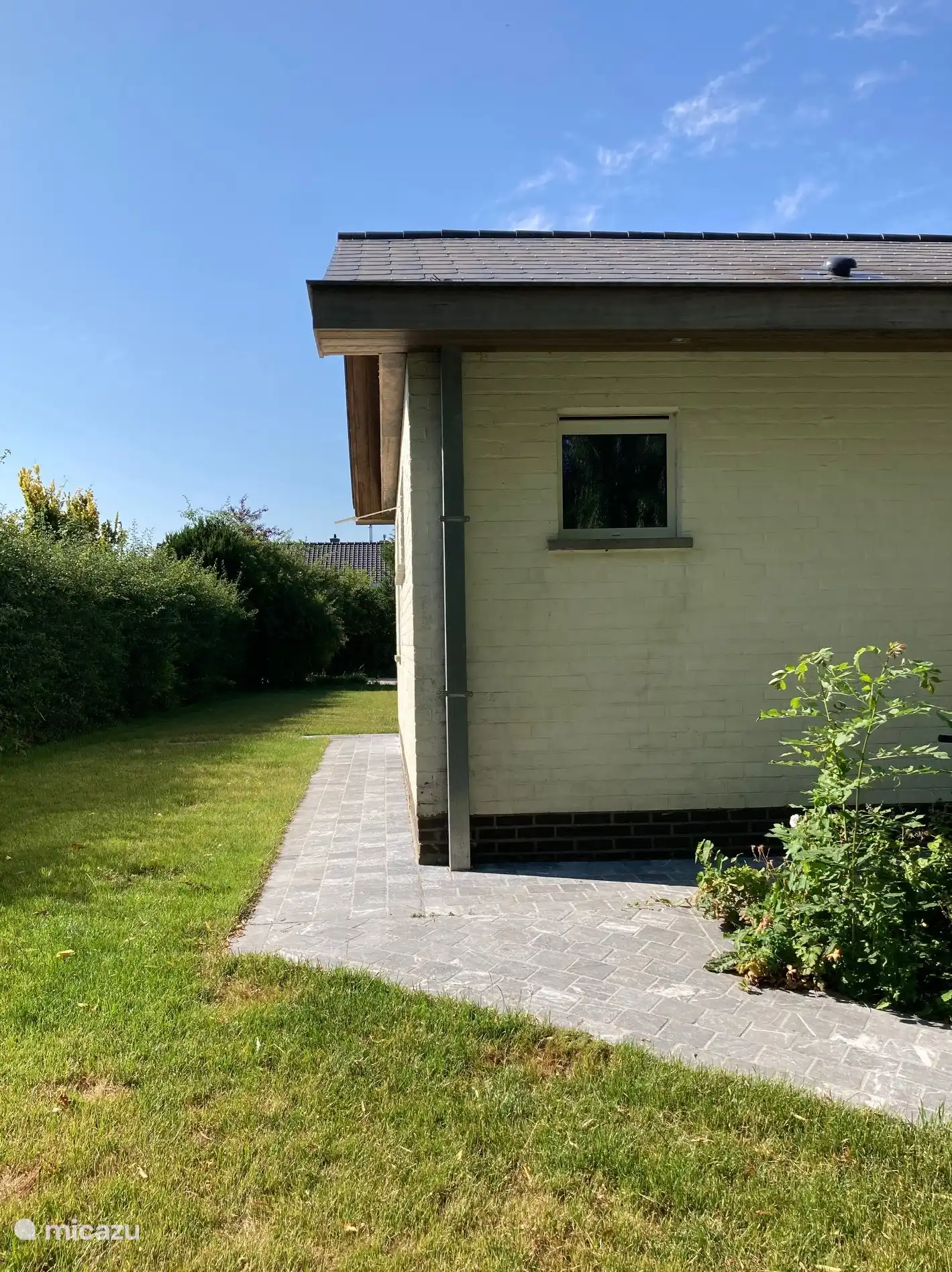 zicht van aan de ingang van de woning en de private tuin naar de oprit. Raam van douche die uitgeeft op de tuin.