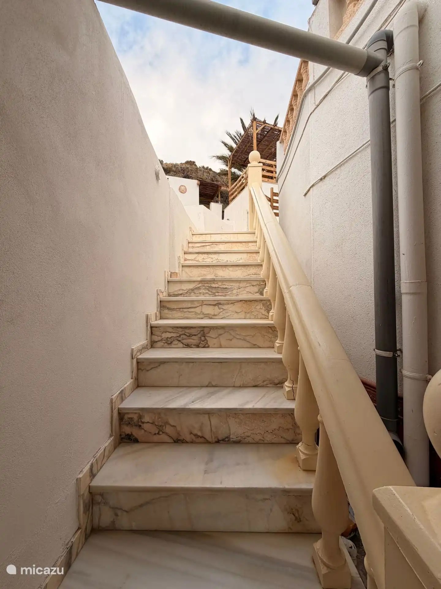 Die Marmortreppe führt Sie nach oben, auf die Terrasse im ersten Stock, aber auch zum Swimmingpool, zum Lounge-Sofa und zu den überdachten Sitzbereichen. (Und der Kühlschrank am Pool). 