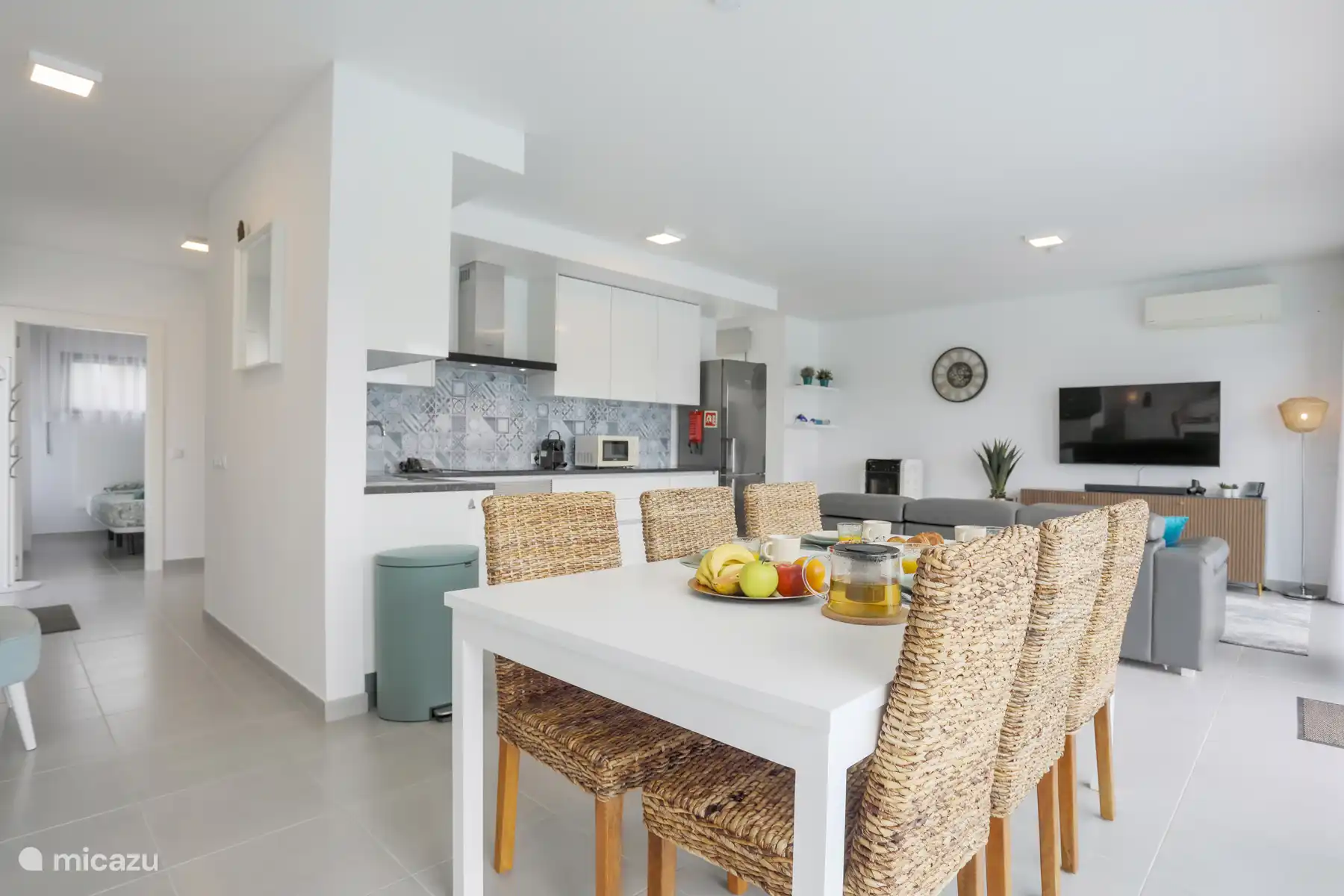 Salon avec cuisine ouverte, table à manger et coin salon. Voir une partie du poêle à palettes peut être vu sous l’horloge. 