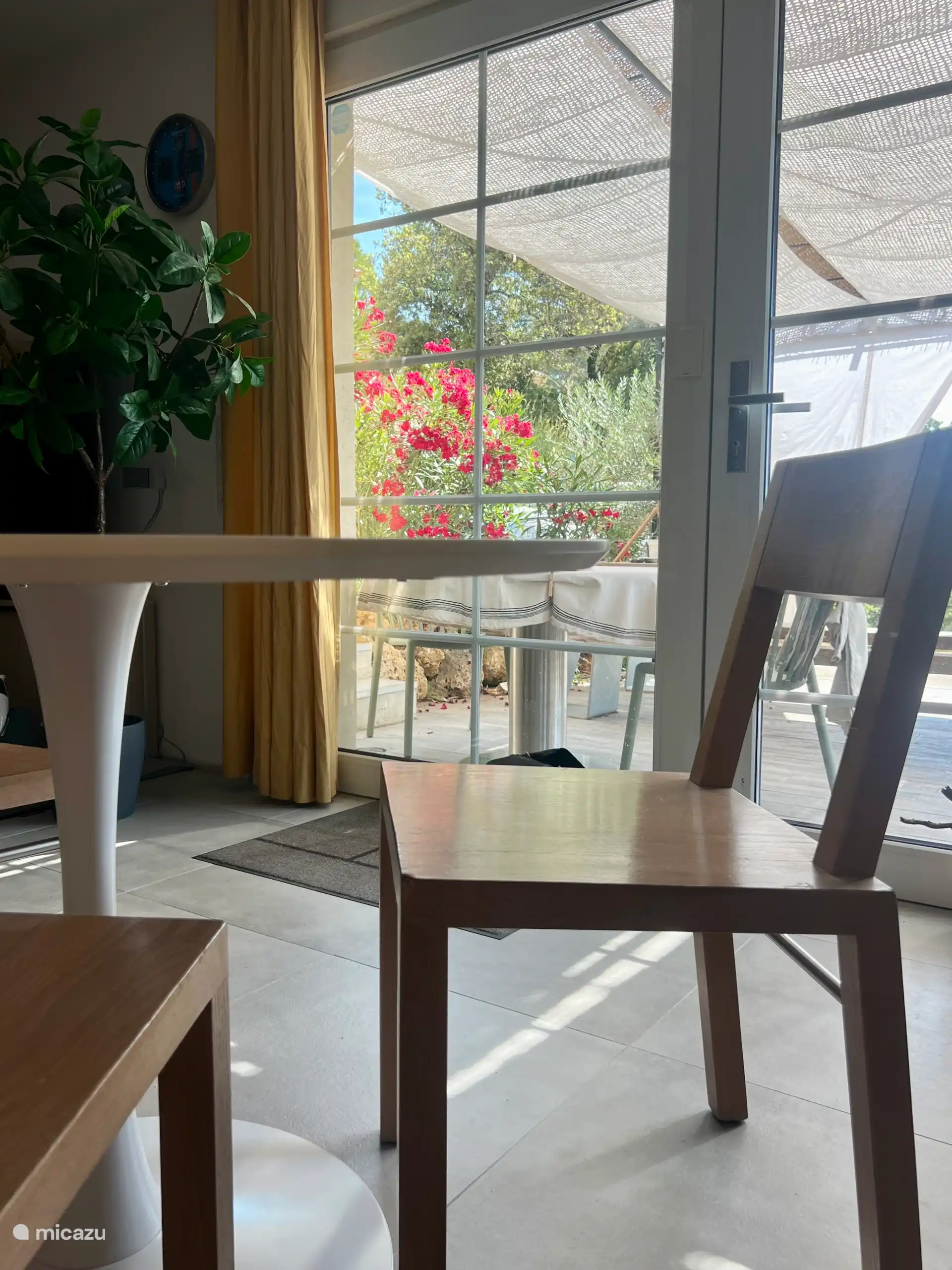 Binnen is een royale ronde twee persoons tafel met uitzicht op het terras.