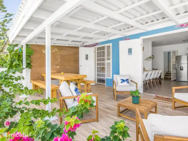 SOMETHING ELS huren in Curaçao, Banda Ariba (oost), Marie Pampoen - vakantiehuis Disfrute de una amplia y luminosa terraza con muebles de madera, rodeada de flores tropicales. El lugar perfecto para relajarse y crear momentos inolvidables.