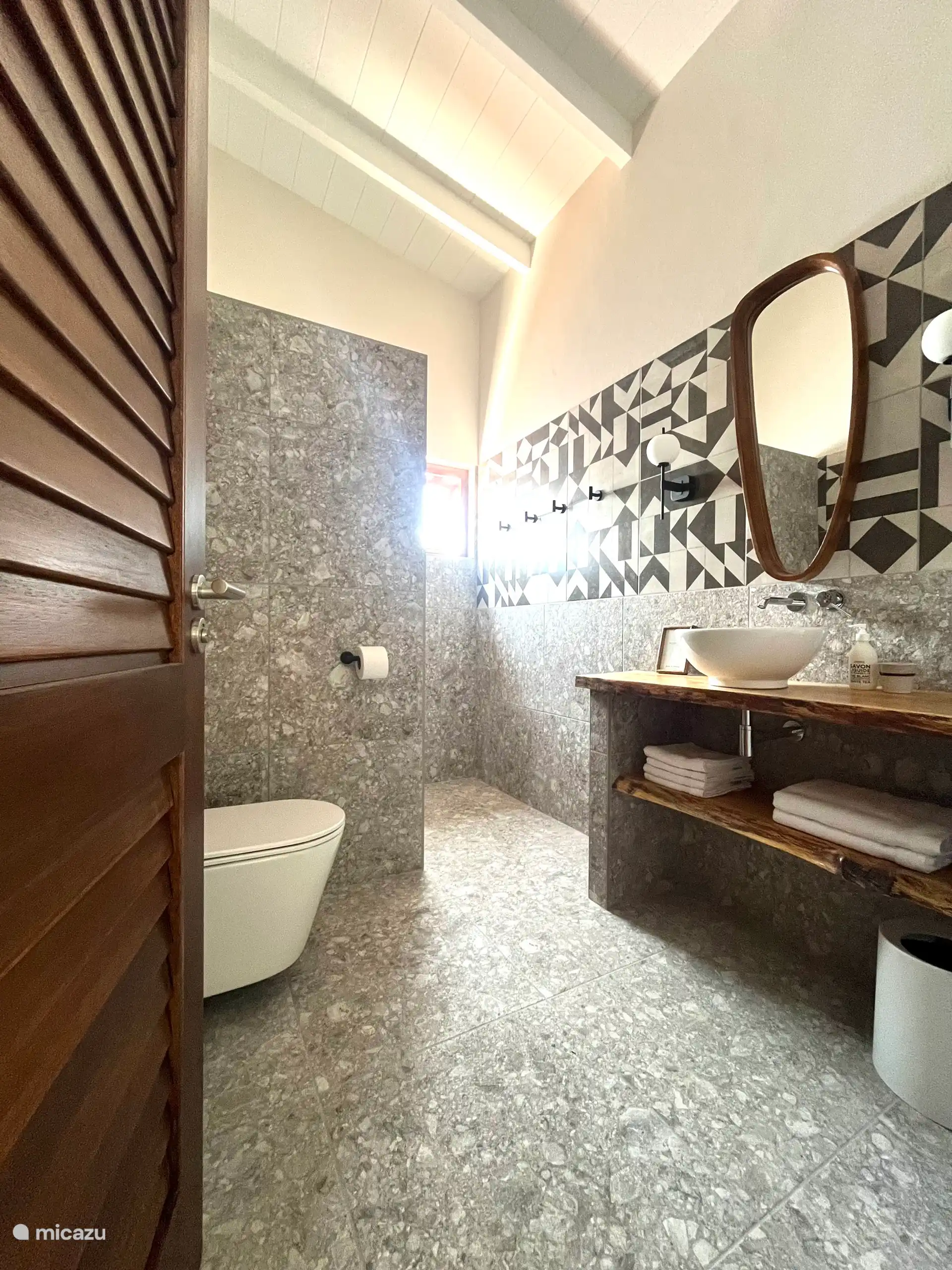 La salle de bain a l’air spacieuse en raison de la hauteur sous plafond et a un intérieur calme. Il y a un sèche-cheveux, du savon pour les mains et bien sûr des serviettes. La douche de tête avec PowderRain offre une détente complète.