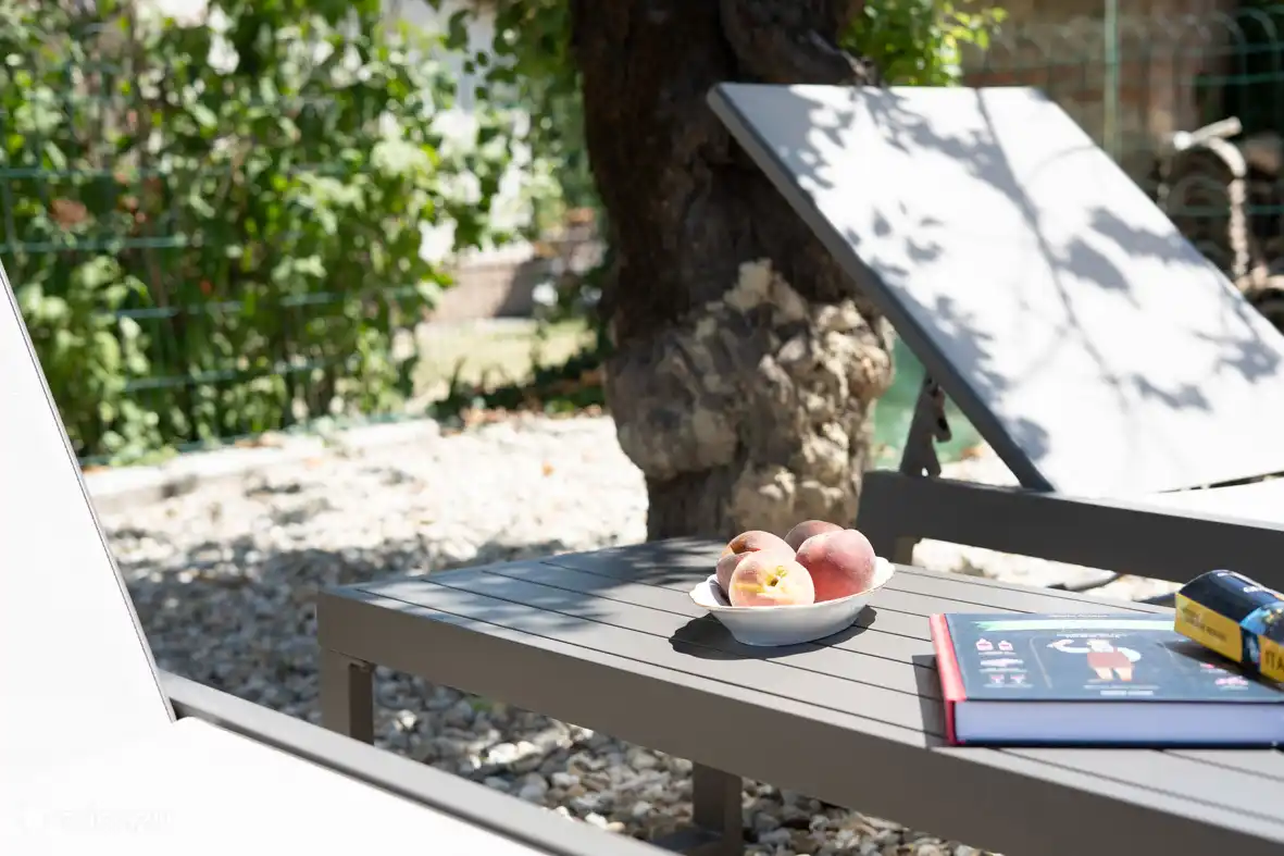 Mit einem Buch in der Sonne. Sie haben einen eigenen Garten mit einem Lounge-Sofa, Sonnenliegen und einem Essbereich