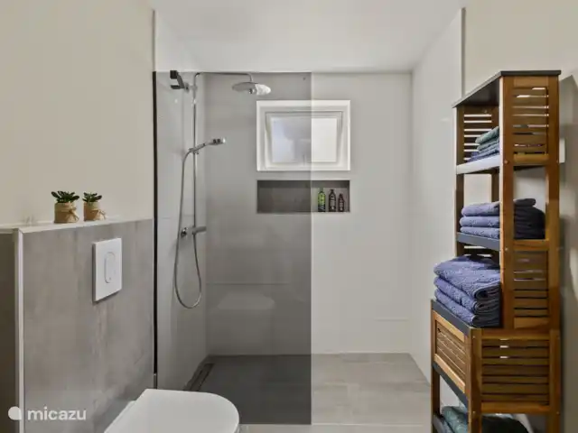 Appartement Mambo Beach | Curaçao, Banda Ariba (est), Bapor Kibra - appartement La salle de bains est élégamment meublée avec une douche moderne, des toilettes flottantes, un lavabo avec miroir et des serviettes Walra douces et un tapis de bain.