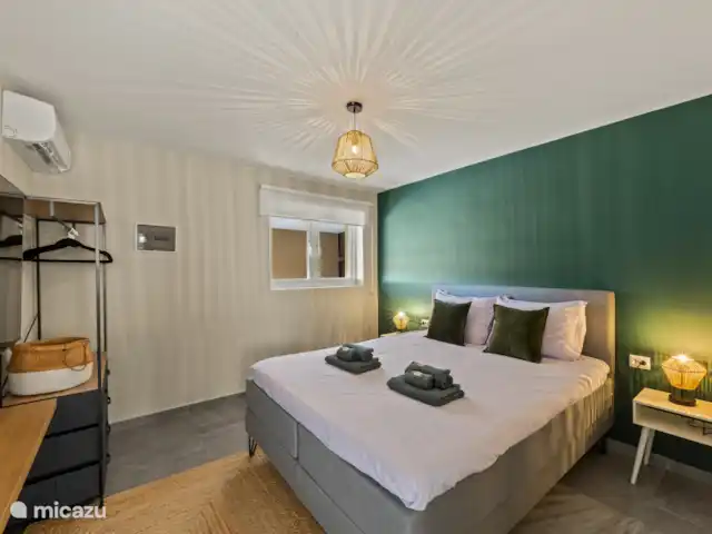 Appartement Mambo Beach | Curaçao, Banda Ariba (est), Bapor Kibra - appartement La chambre est meublée d’un lit luxueux comprenant un surmatelas confortable, d’une armoire spacieuse et de sa propre télévision de 55 pouces. Grâce à l’éclairage d’ambiance, vous pouvez profiter d’un confort et d’une détente ultimes