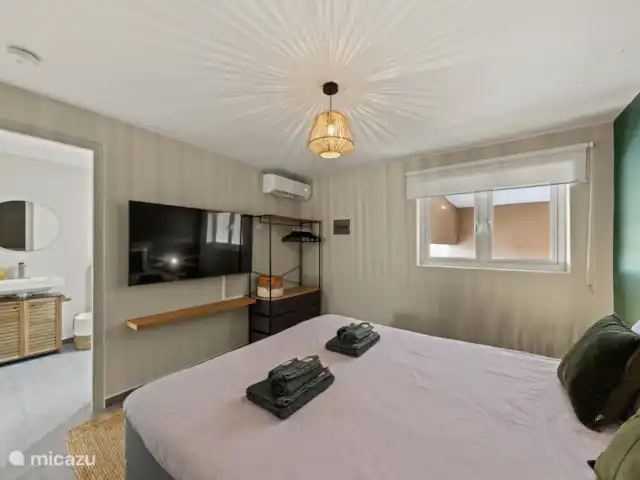 Appartement Mambo Beach | Curaçao, Banda Ariba (est), Bapor Kibra - appartement La chambre est meublée d’un lit luxueux comprenant un surmatelas confortable, sa propre télévision de 55 pouces. Grâce à l’éclairage d’ambiance et à la climatisation, vous pouvez profiter d’un confort et d’une détente ultimes ici