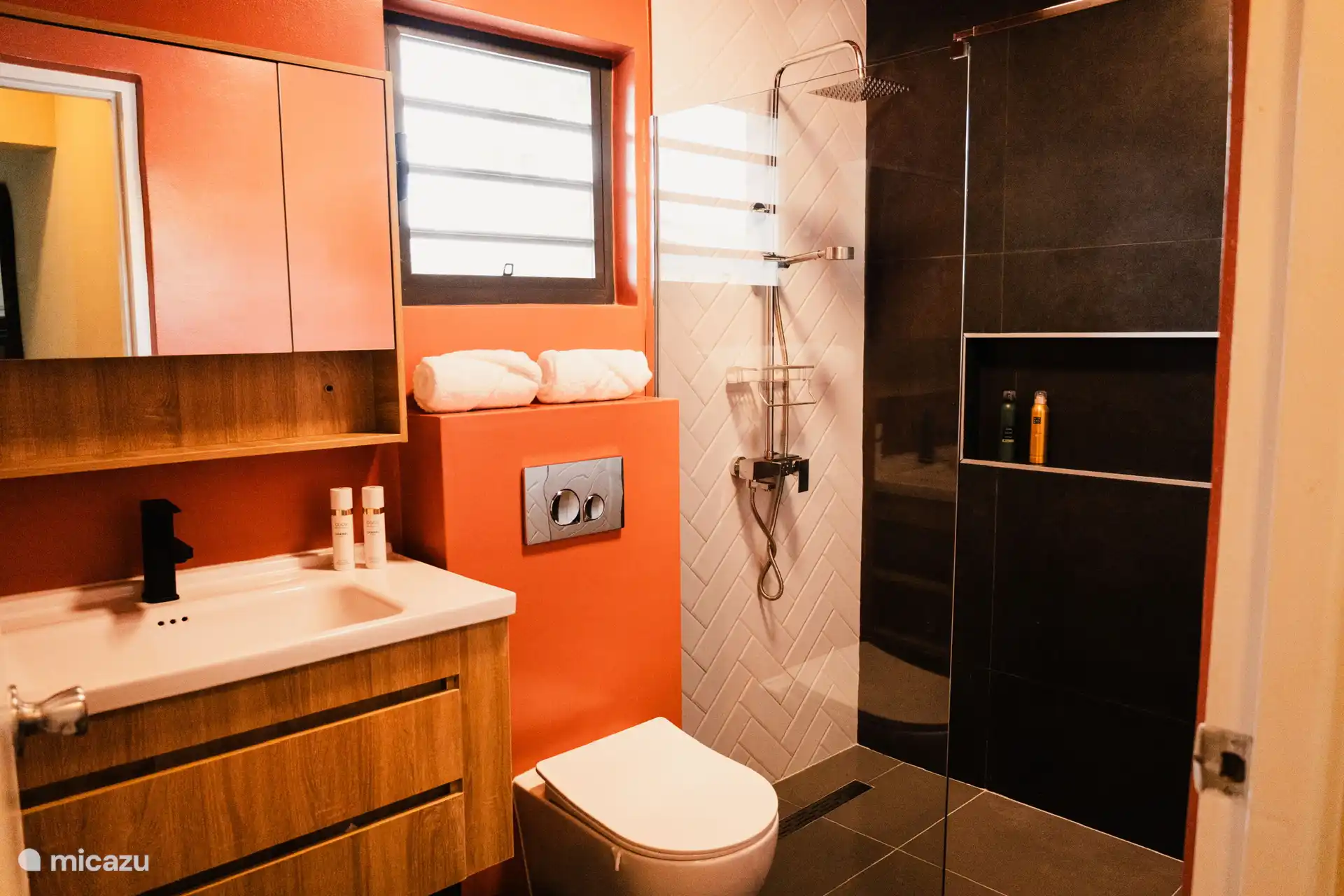 Baño moderno con ducha de lluvia, colores cálidos y detalles claros. Maravillosamente refrescante después de un día en la playa.