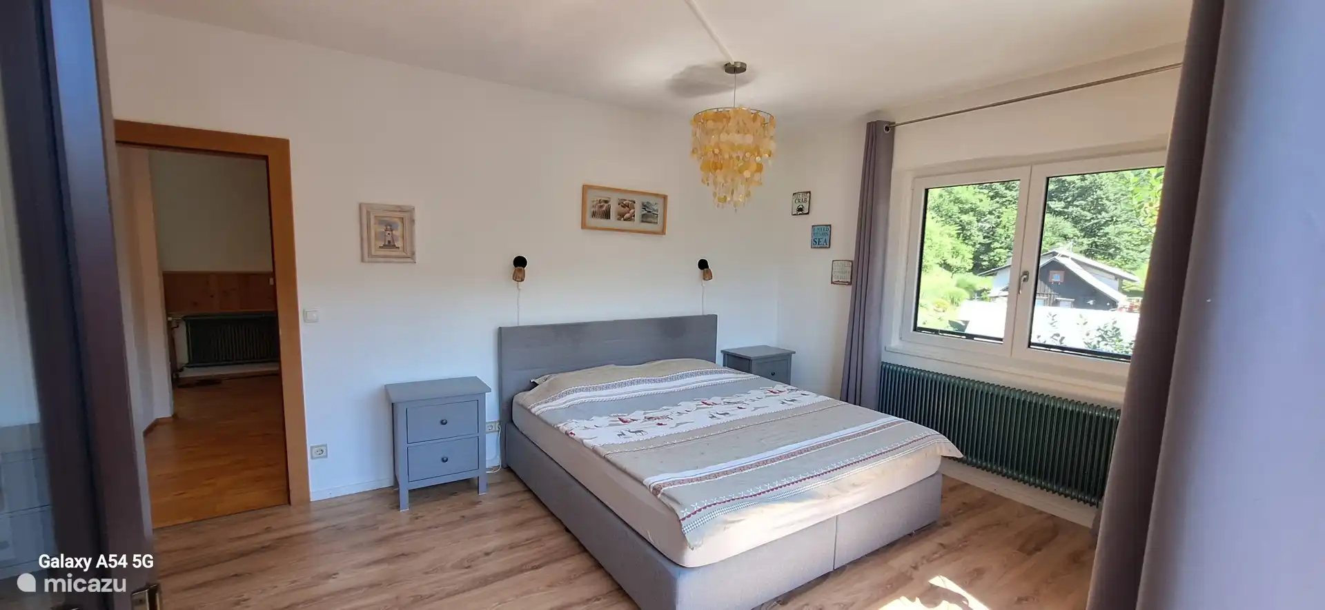 Hauptschlafzimmer. Boxx Ring 1,80 x 2,00. Ein großer Kleiderschrank mit verspiegelter Tür. Rechts ein Blick auf die Straße in Richtung Forstweg. 