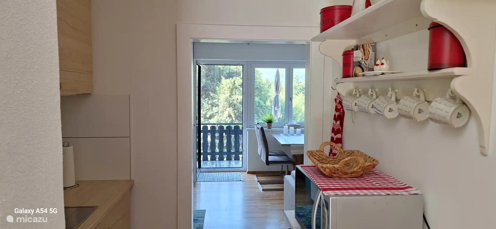 Blick vom Flur durch den nassen Küchenteil zum Essbereich im Wohnzimmer. Dahinter Balkon.