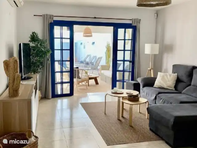 Casa Raina | Espagne, Lanzarote, Playa Blanca - villa De la cuisine, vous entrez dans le salon et la salle à manger décloisonnés. Il dispose d’un canapé confortable, de la climatisation et d’une télévision avec des chaînes internationales. Voici un accès à la véranda par des portes-fenêtres.