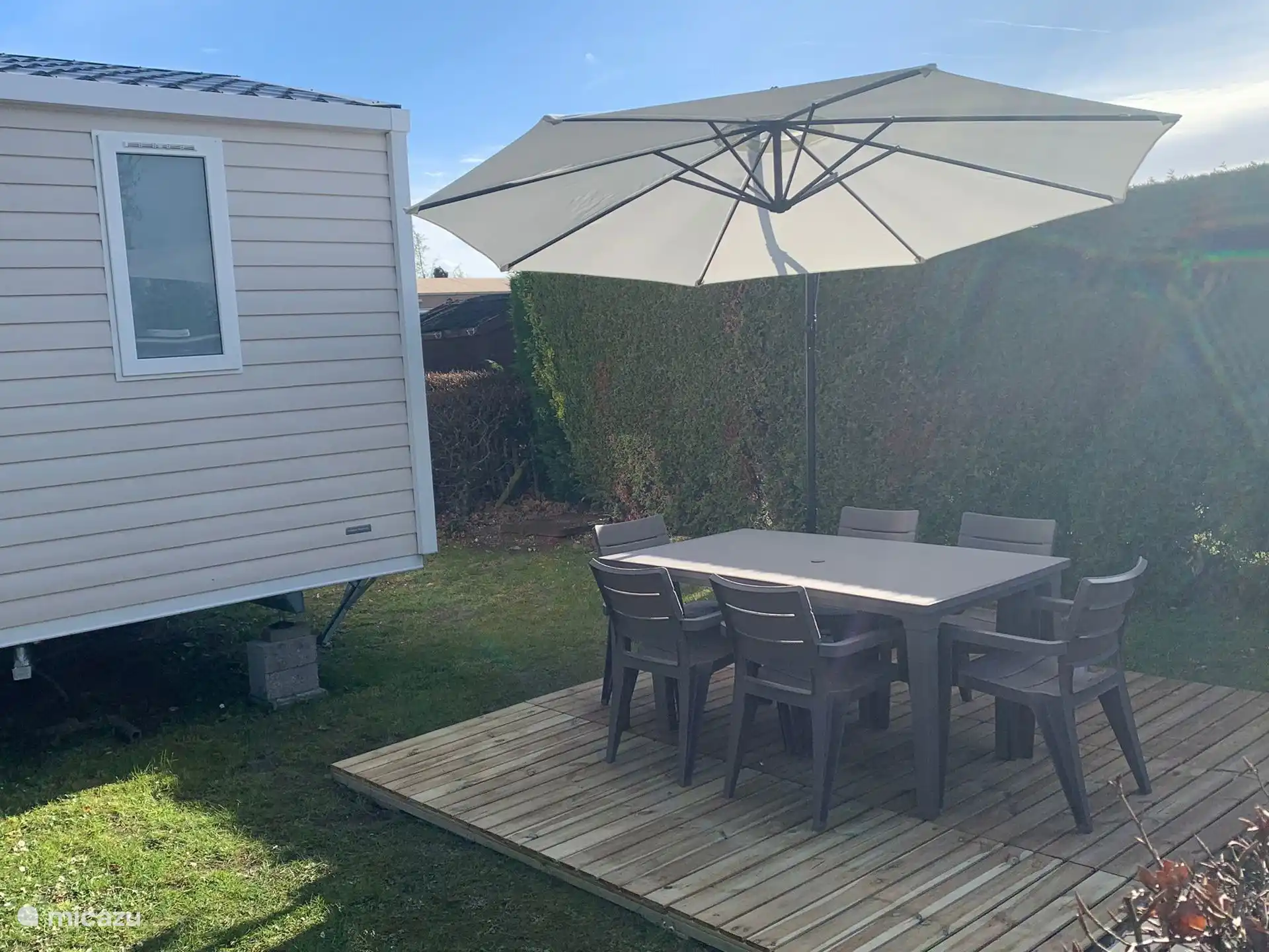 Pequeña terraza con mesa de jardín, seis sillas y sombrilla