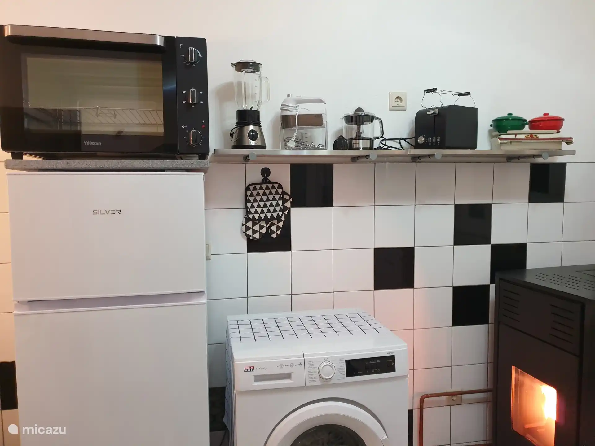 De keuken met koelkast, oven, wasmachine, diverse keukenapparatuur en de caldeira: De kachel die voor de centrale verwarming in het hele huis zorgt.