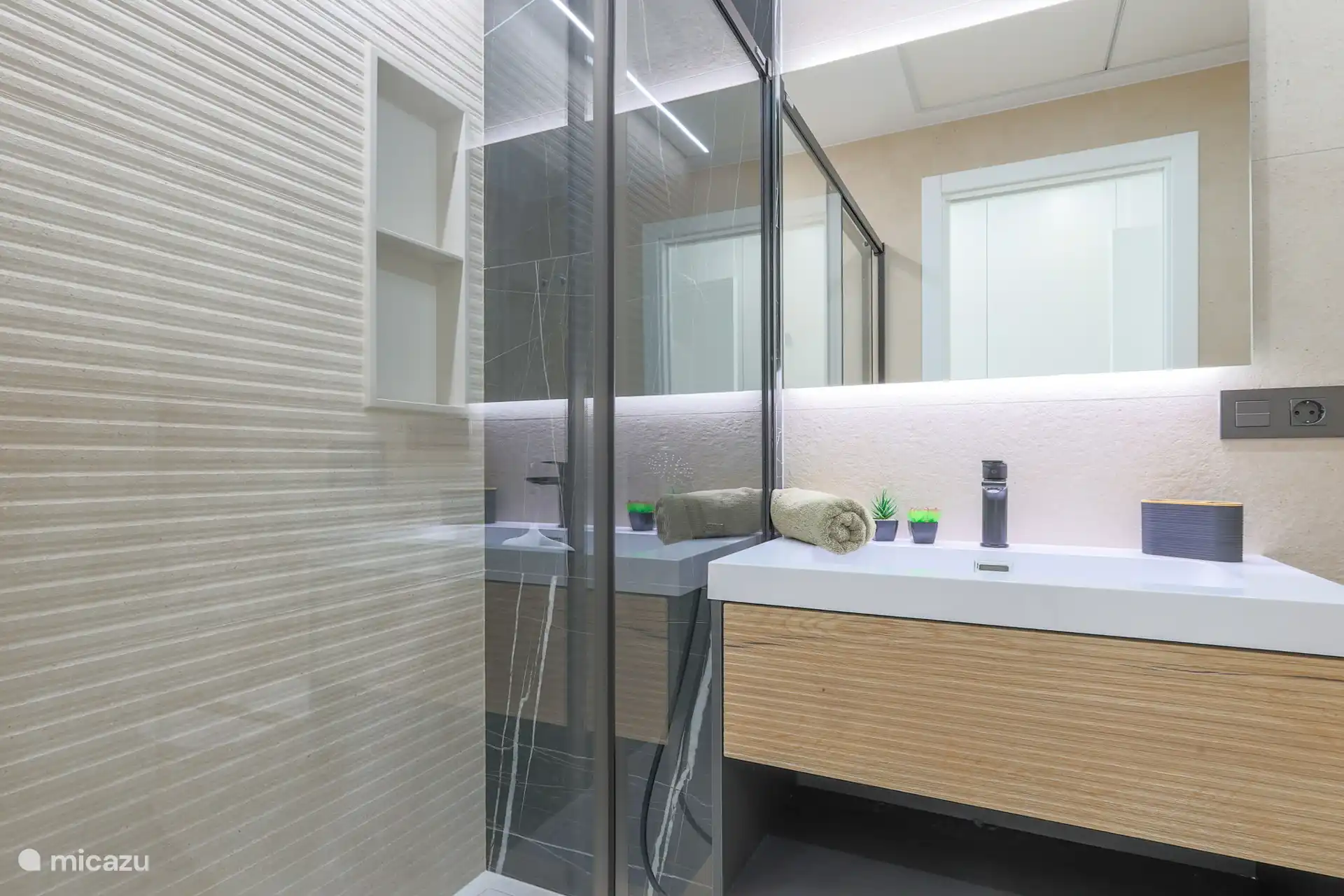 Salle de bain attenante, équipée d’une grande douche à effet pluie, de toilettes et d’un lavabo spacieux.