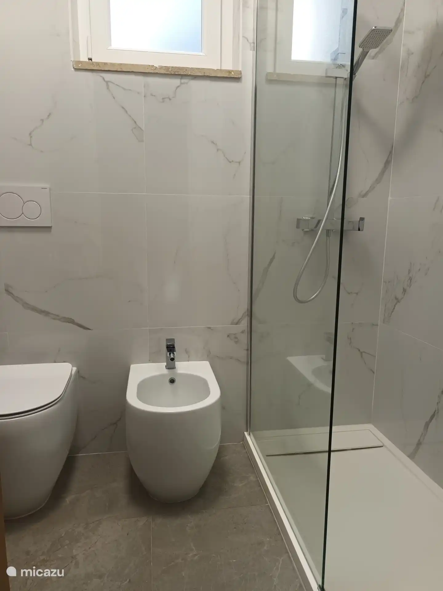 Baño con cabina de ducha, bidé e inodoro.