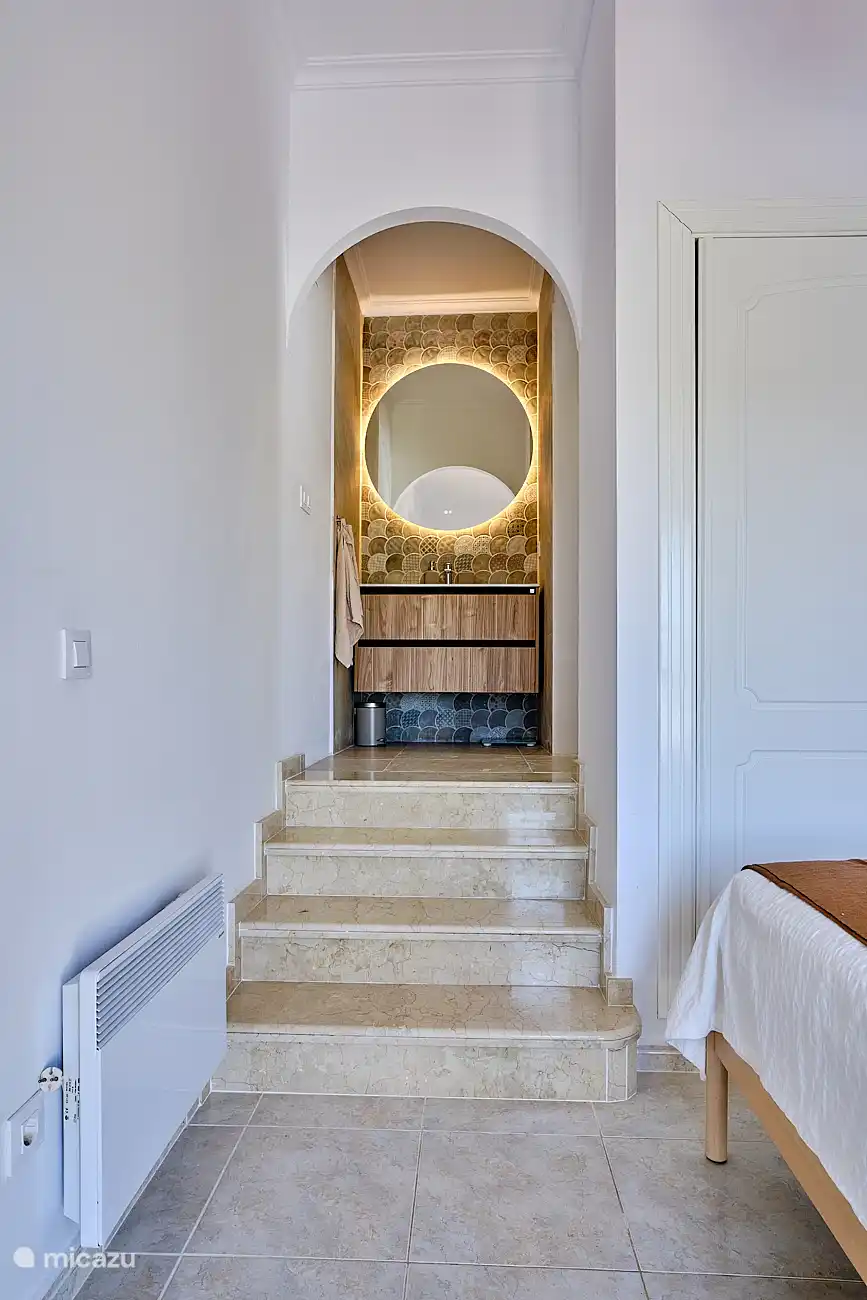 Ensuite Badezimmer mit Waschbecken, ebenerdiger Dusche und WC.