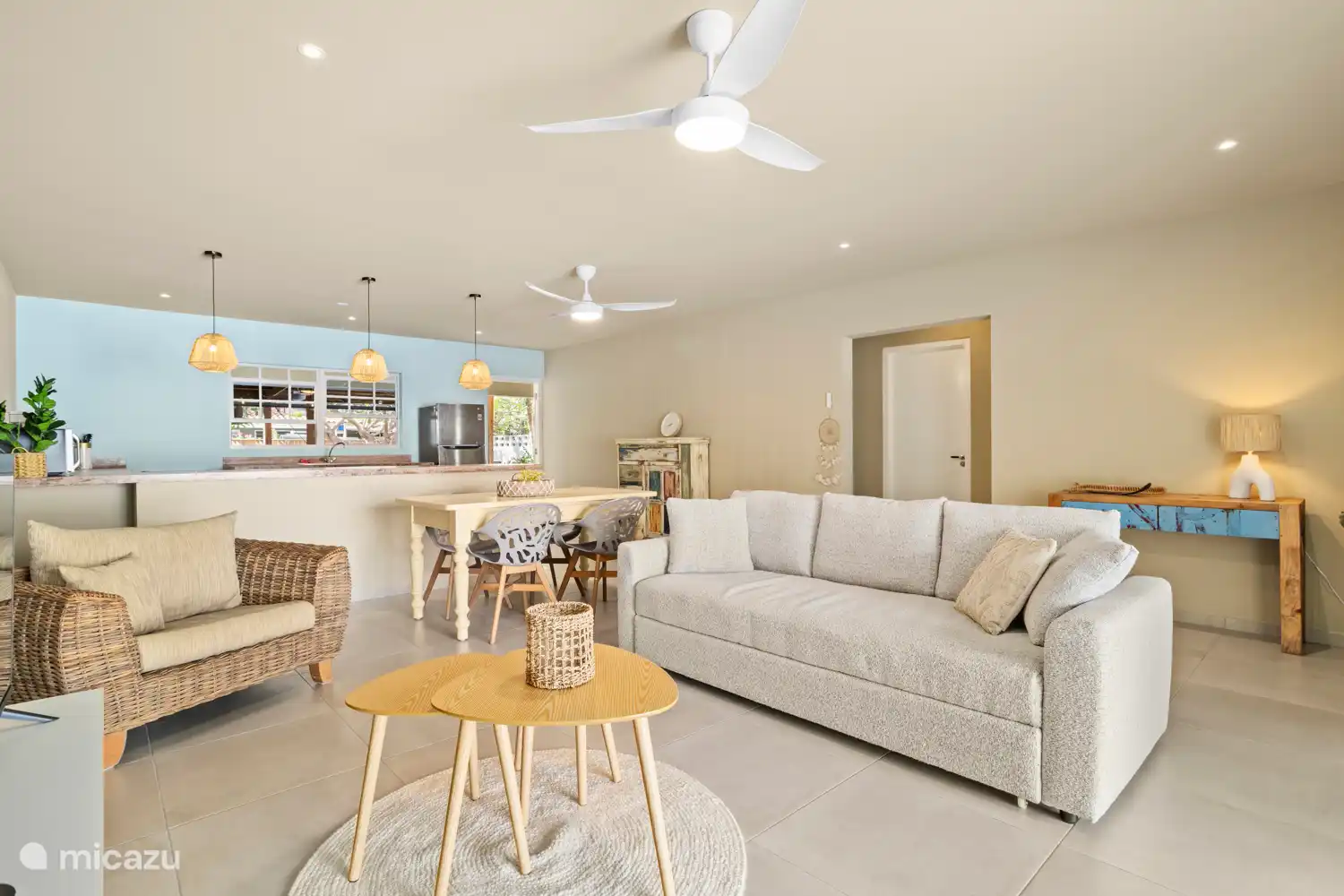 Woonkamer met comfortabele slaapbank, eettafel en open keuken.