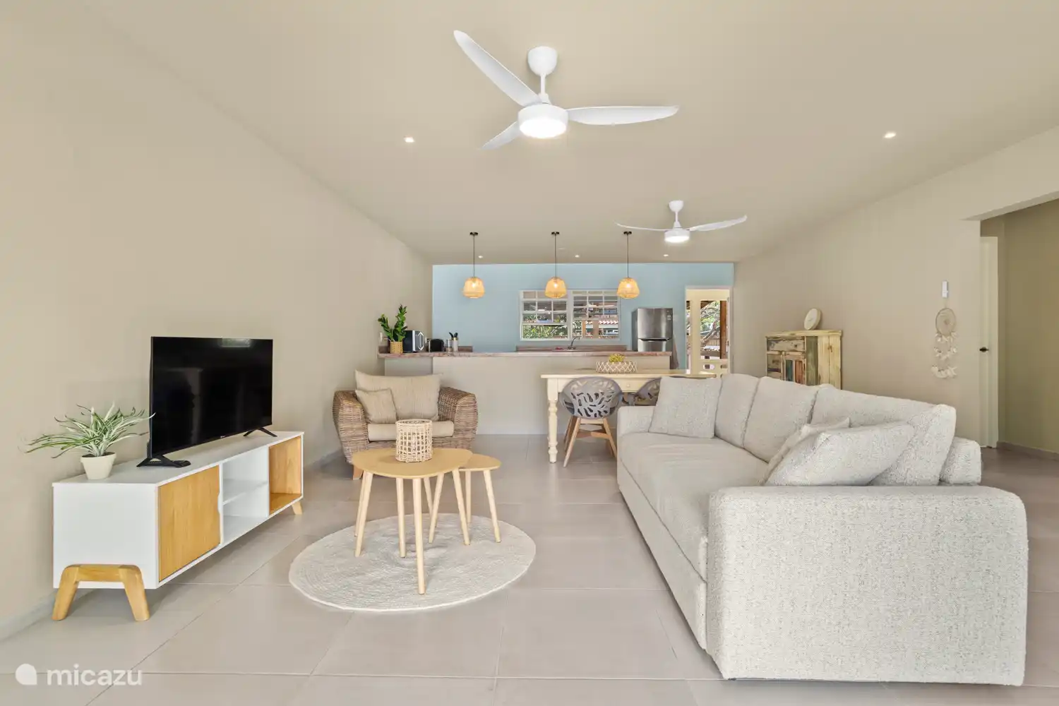 Woonkamer met comfortabele slaapbank, TV, eettafel en open keuken.