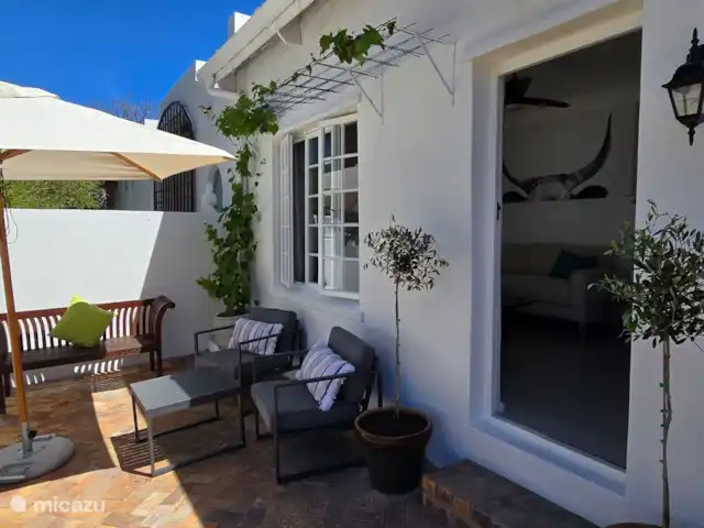 apartamento en Sudáfrica, Cabo Occidental, Somerset Oeste – El apartamento de vacaciones Lodge  Acogedora terraza soleada con un sofá de teca de 2 plazas, dos sillas de terraza con mesa auxiliar y sombrilla