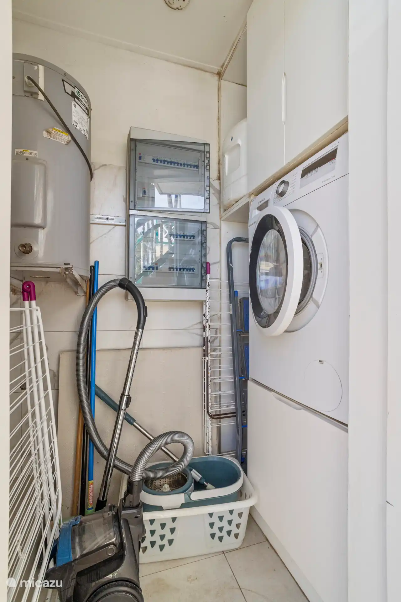 Buanderie avec machine à laver, aspirateur, panier à linge et étendoir