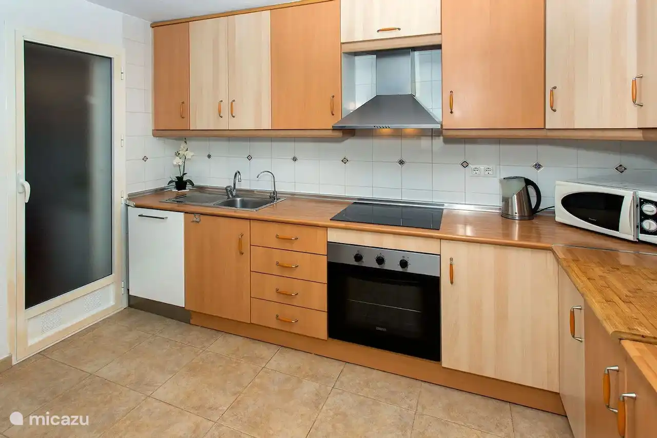 Cocina equipada con espacio de almacenamiento contiguo (lavadora y tendedero).