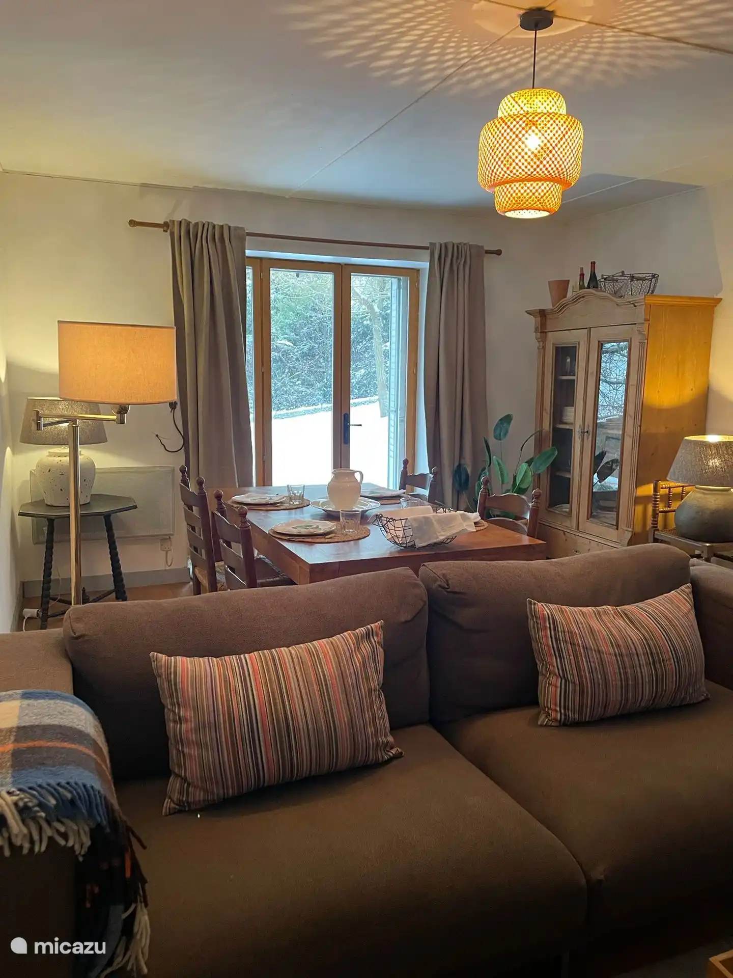 Comfortabele woonkamer met zithoek, eettafel en openslaande deuren naar aangrenzende tuin.