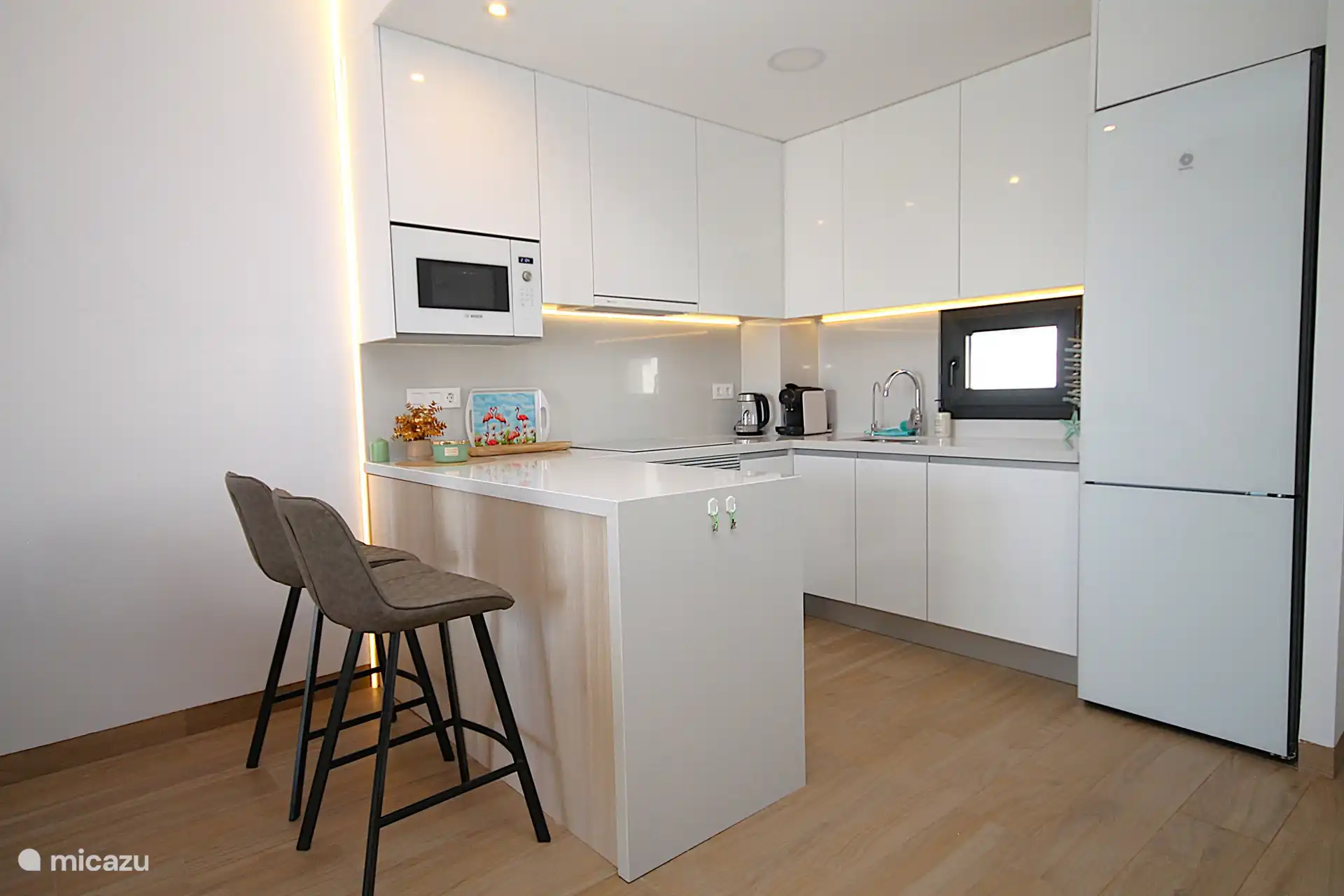 Luxuriöse offene Küche mit Induktionskochfeld, Dunstabzugshaube, Kombi-Mikrowelle, Kombi-Backofen, Geschirrspüler, Wasserfiltersystem und Kühlschrank mit Gefrierfach.