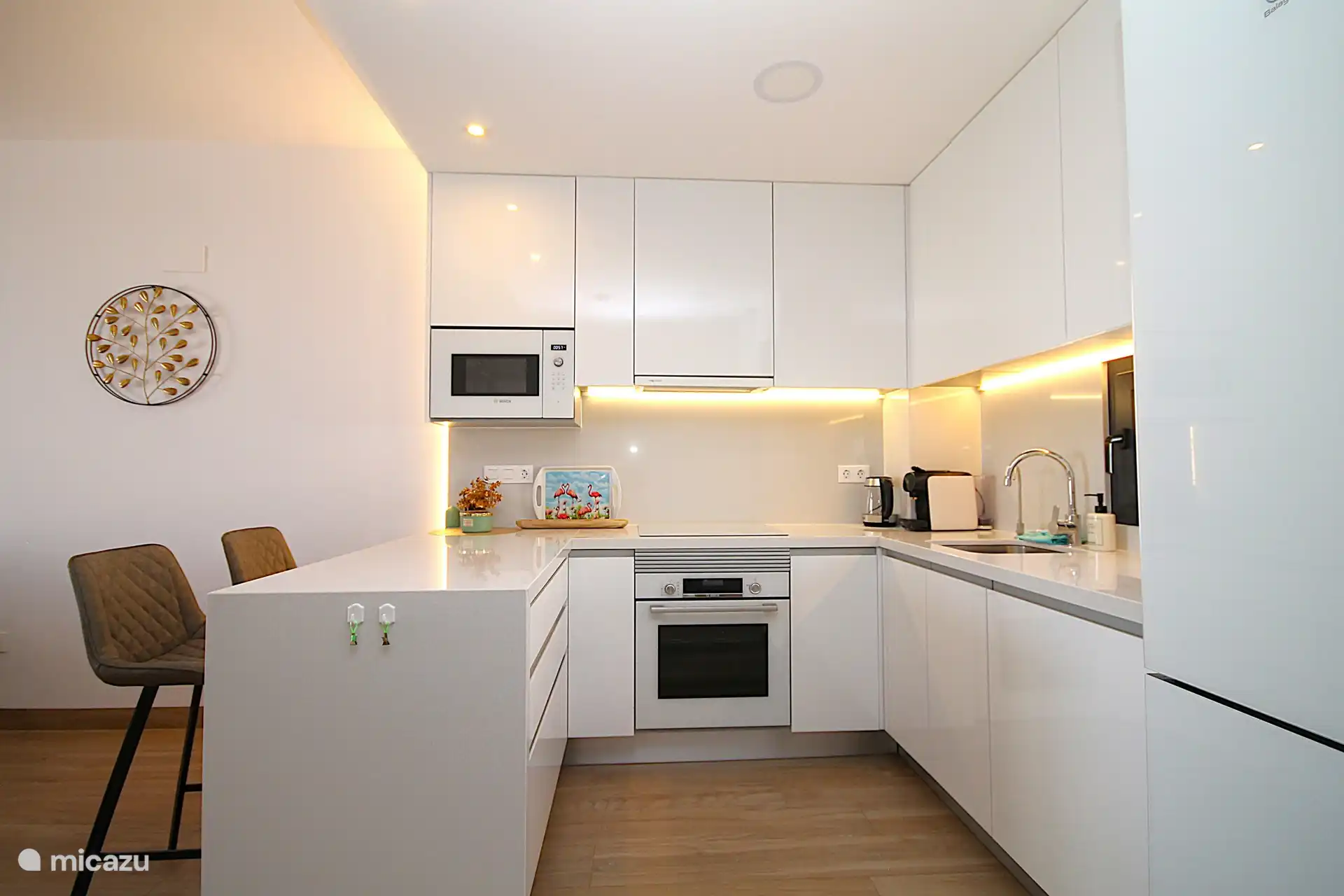 Luxuriöse offene Küche mit Induktionskochfeld, Dunstabzugshaube, Kombi-Mikrowelle, Kombi-Backofen, Geschirrspüler, Wasserfiltersystem und Kühlschrank mit Gefrierfach.