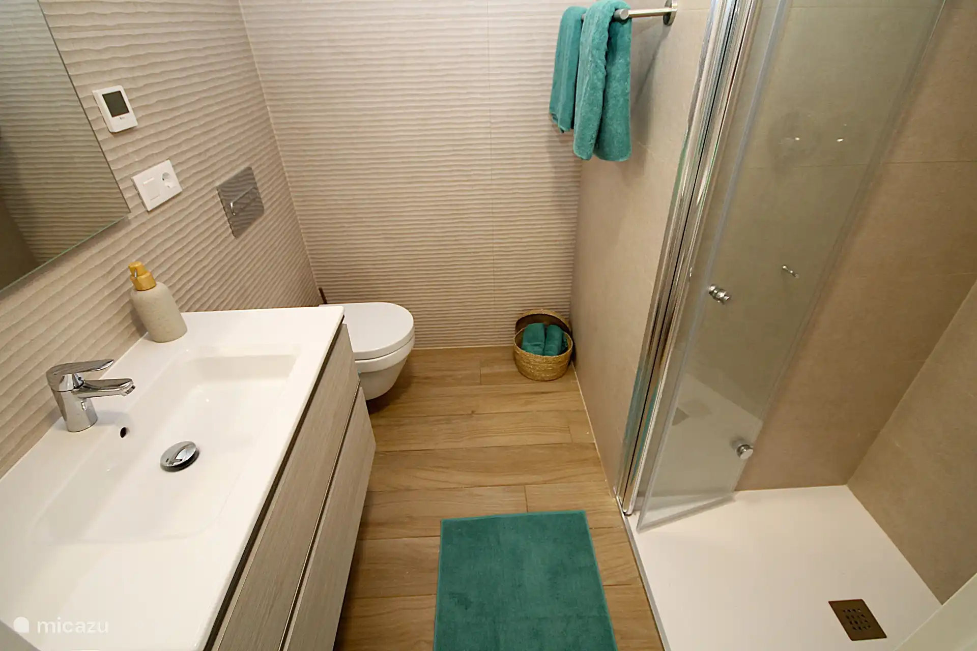 Badezimmer 1 mit Dusche, Waschbecken, Fußbodenheizung und hängendem WC.