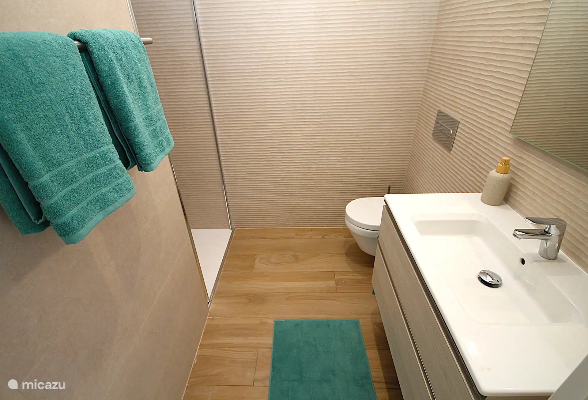 Badezimmer 2 mit Dusche, Waschbecken, Fußbodenheizung und hängendem WC.