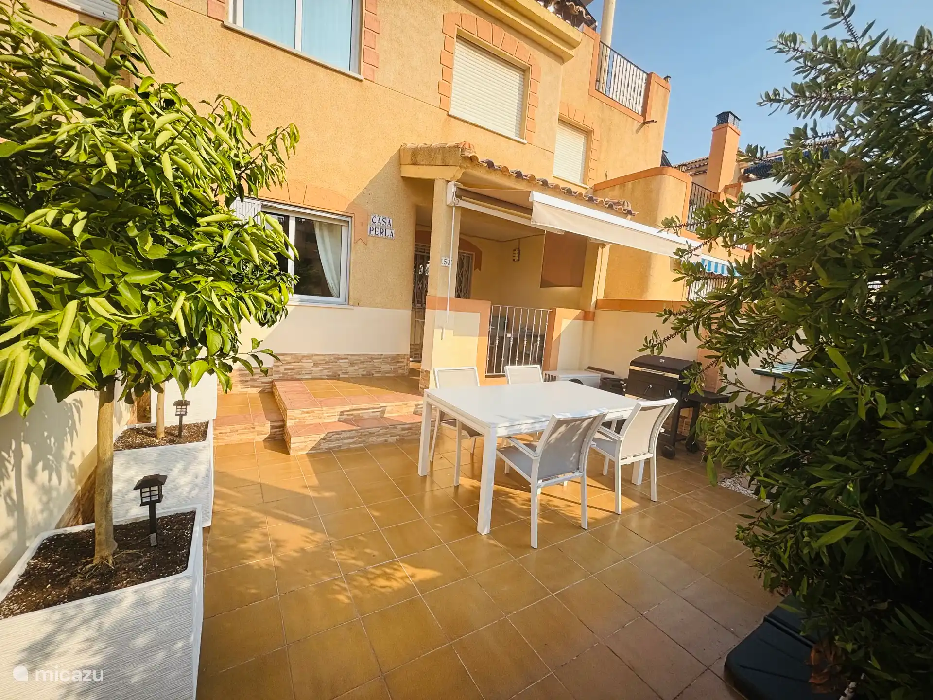 Jardin avec mobilier de jardin, parasol et barbecue.
