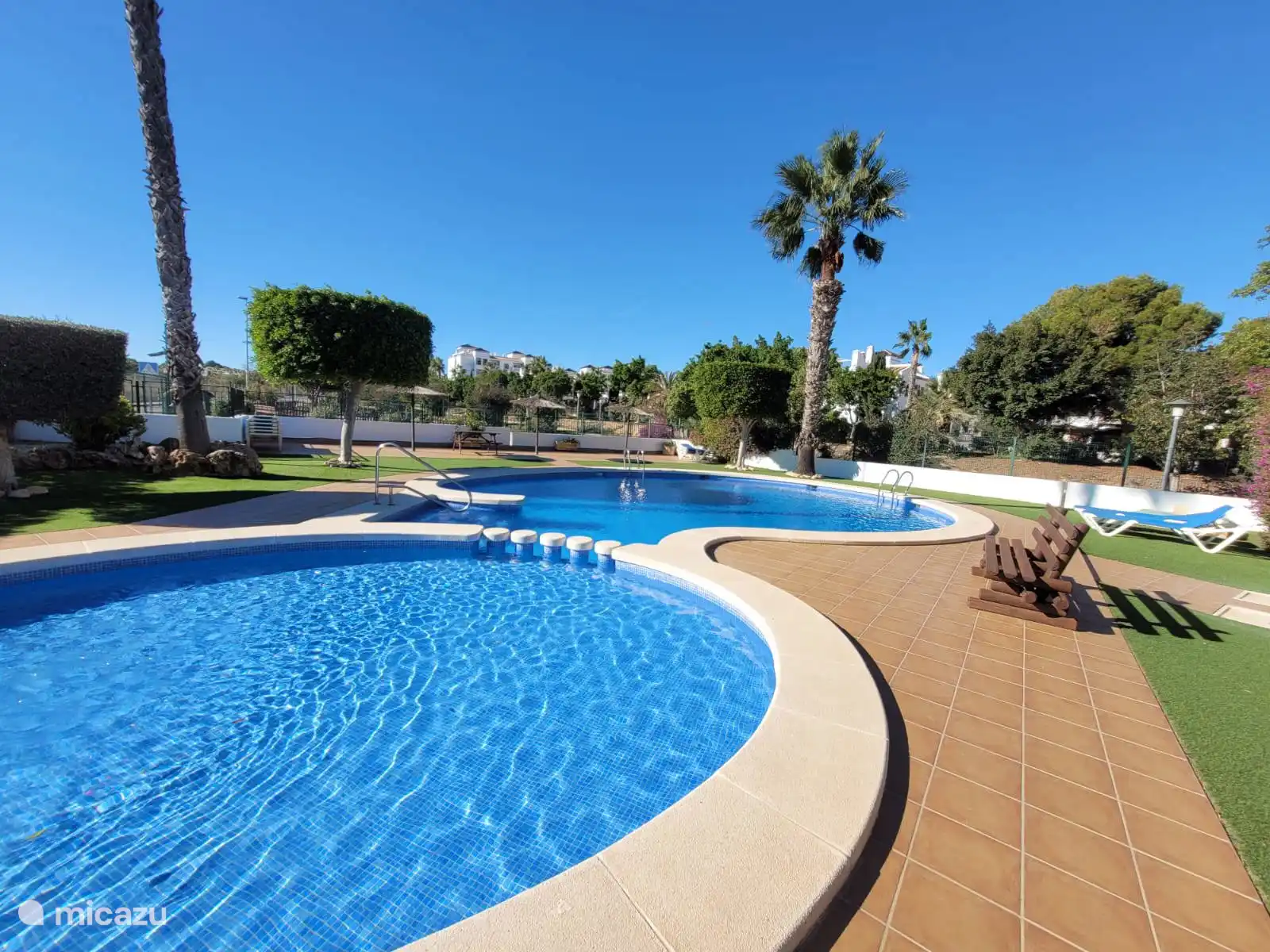 Belle piscine commune avec bassin pour enfants et chaises longues. Détendez-vous sous le soleil espagnol, profitez d’une baignade rafraîchissante et du sentiment de vacances au milieu d’un environnement verdoyant.