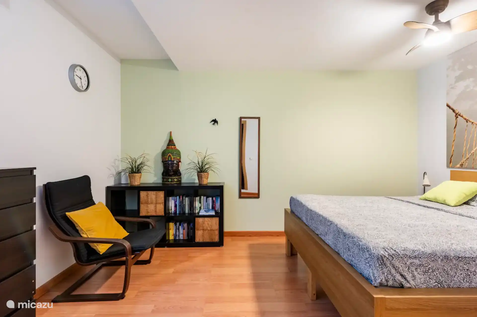 Lit double, commode, tables de chevet, bibliothèque et fauteuil. Chambre fraîche avec ventilateur de plafond. Photo prise sous un angle différent.